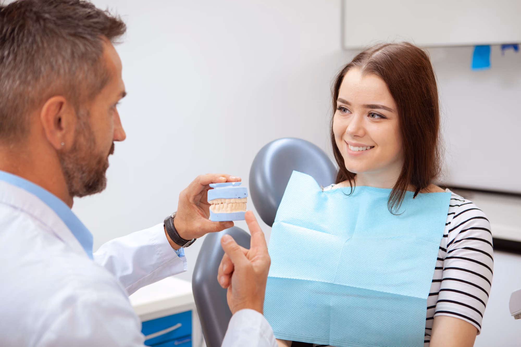 Dentist explaining treatment options to a patient using a dental model during a consultation.