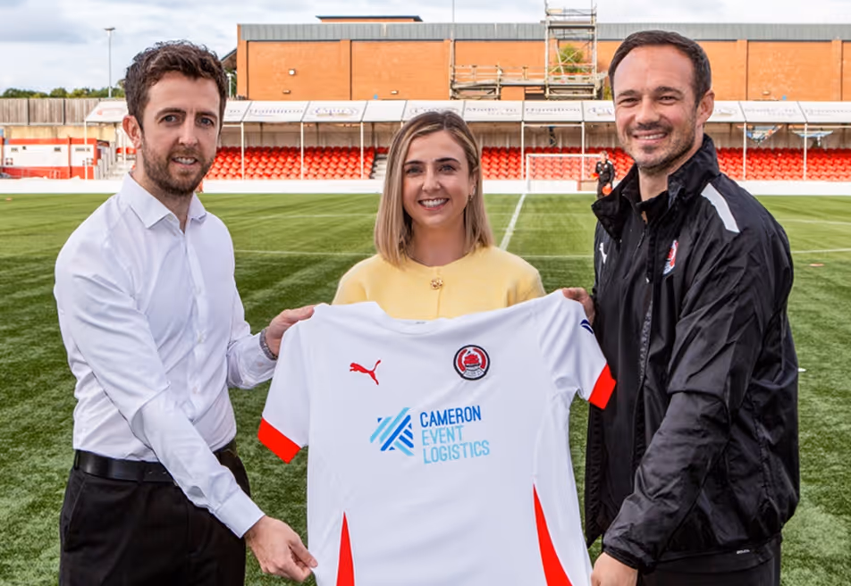 Ewen and Nicole Cameron standing with the Clyde Football Club Manager holding a football shirt.