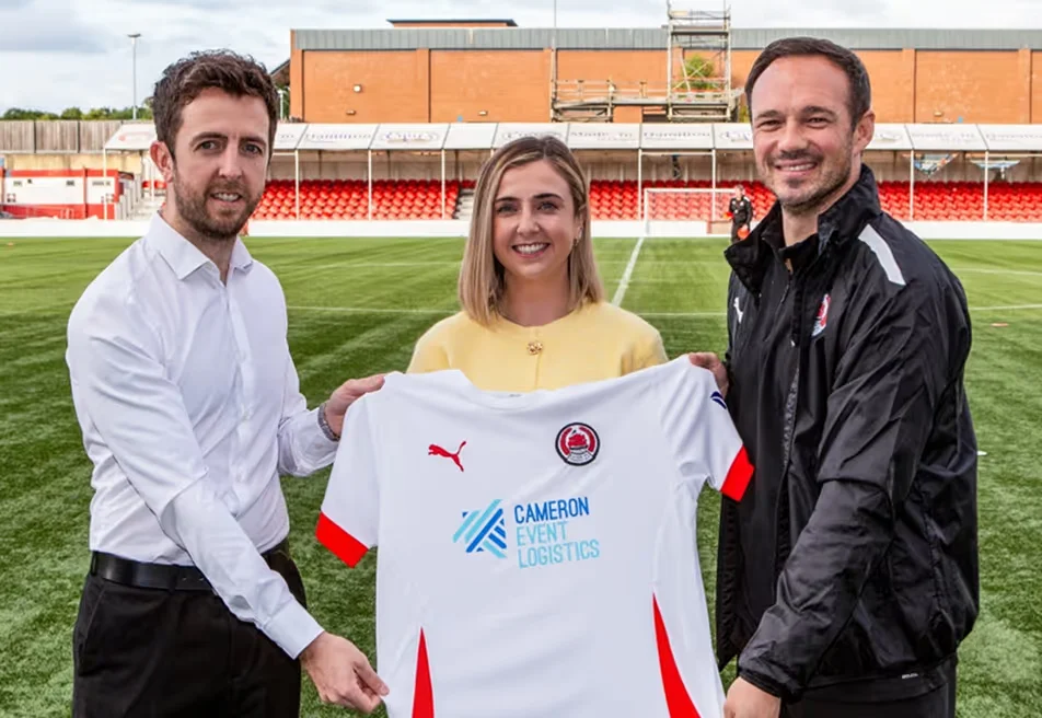 Ewen and Nicole Cameron standing with the Clyde Football Club Manager holding a football shirt.