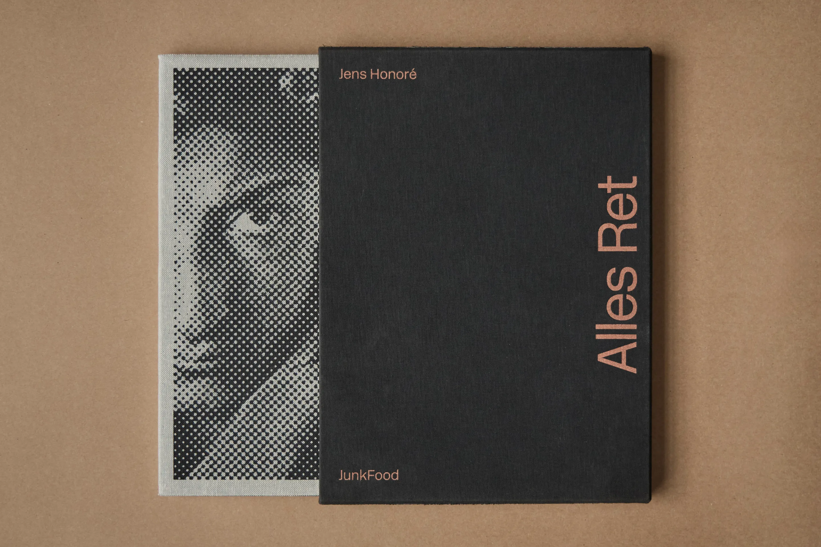 Black book titled 'Alles Ret' by Jens Honoré resting on a grayscale, pixelated image of a face on fabric.