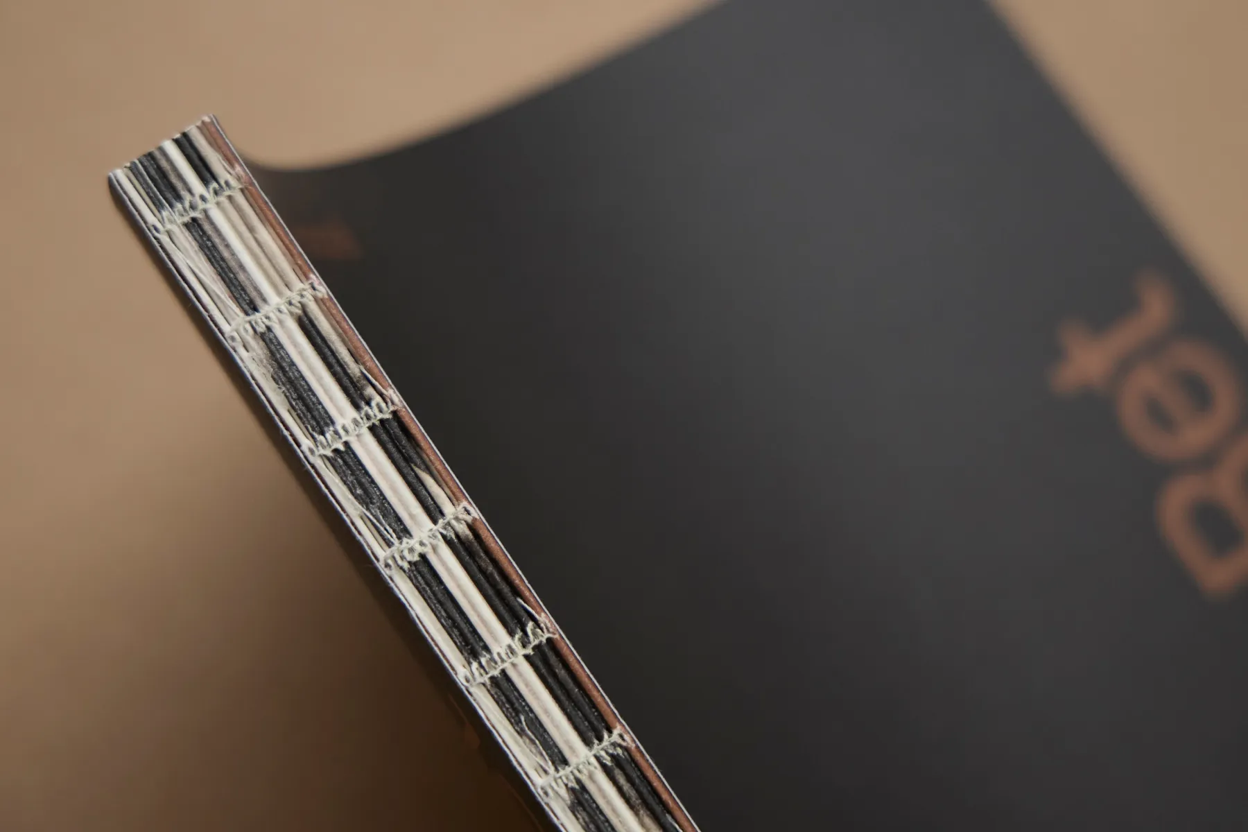 Close-up of a black hardcover book's spine showing its visible stitched binding.