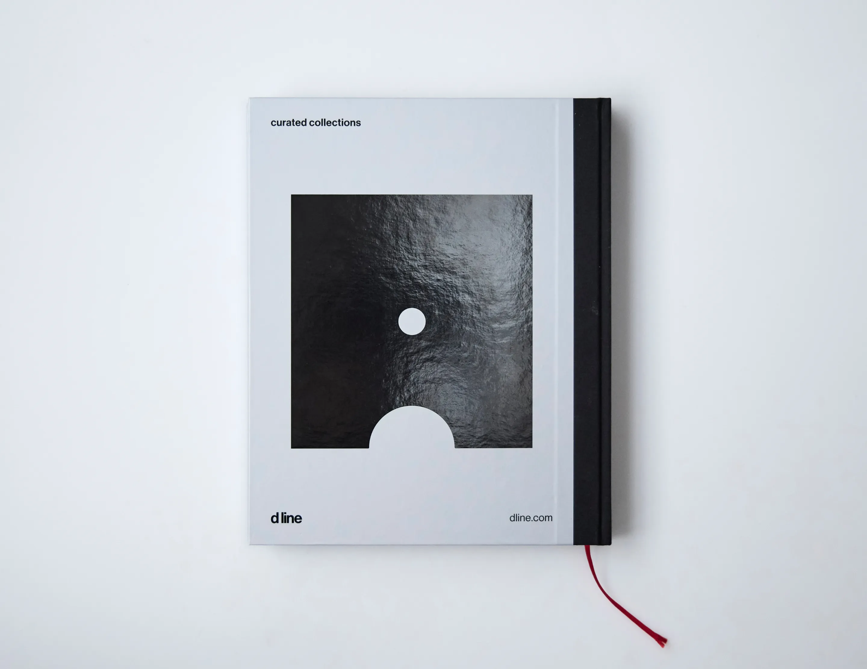Closed gray book with black spine featuring a black square with a white circle and semicircle, titled 'curated collections' and branded 'd line' with dline.com.