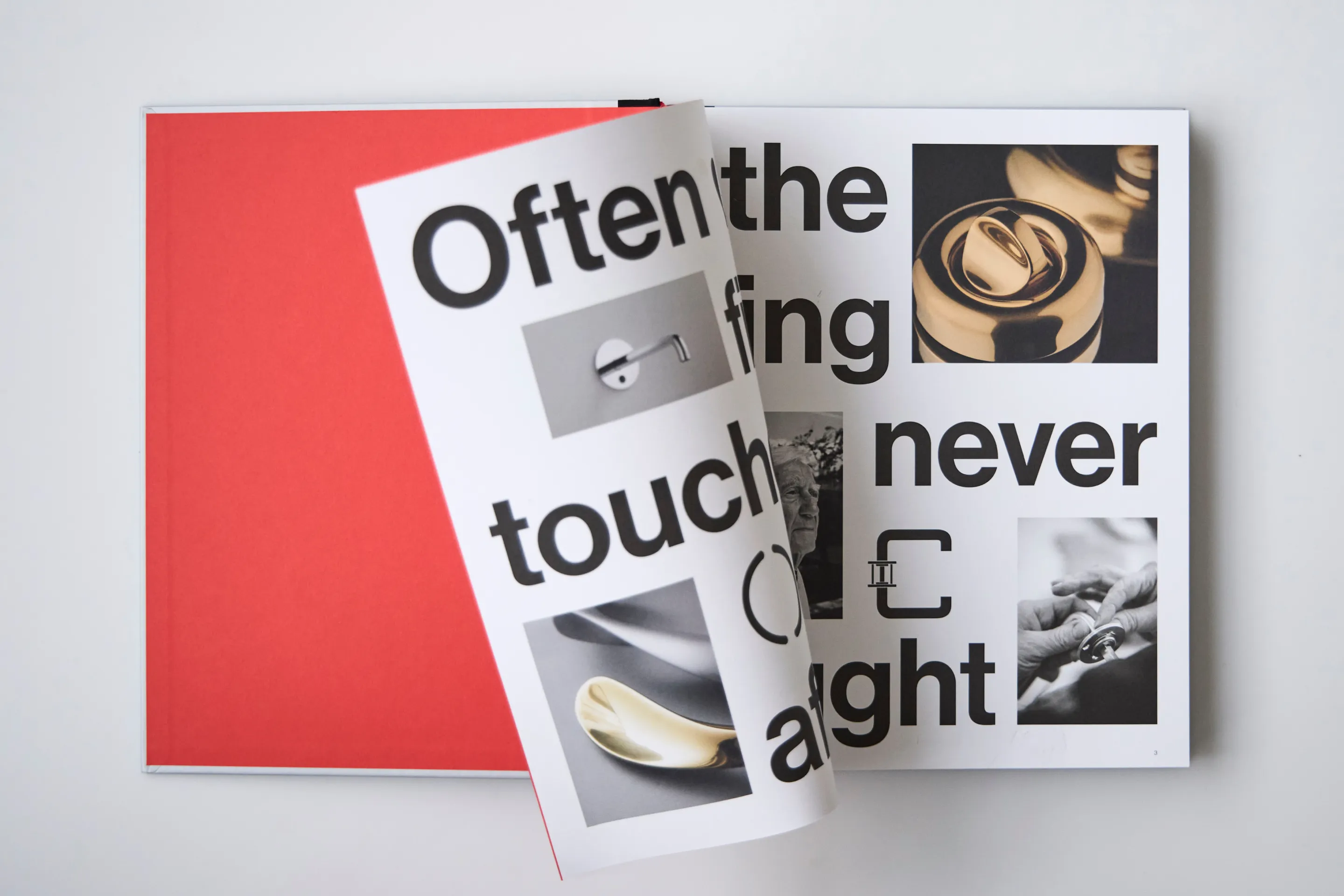 Open book on a white surface showing large bold text and black-and-white images, with a red page turning.