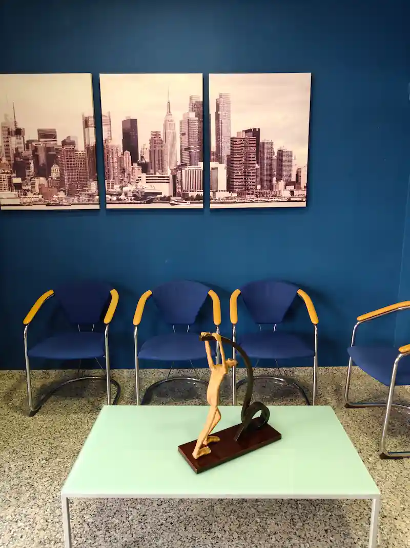 Sala de espera con paredes azules y una mesa de cristal baja con una figura