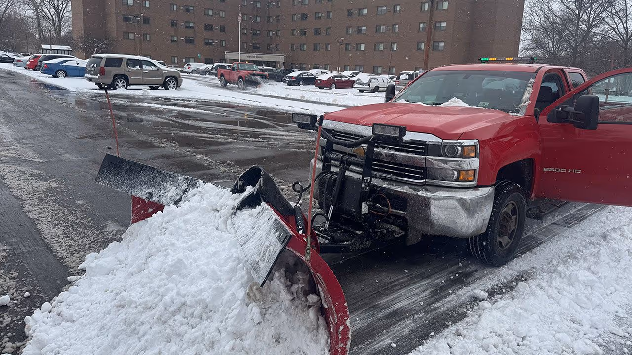 Snow plow truck clearing large commercial lot near me