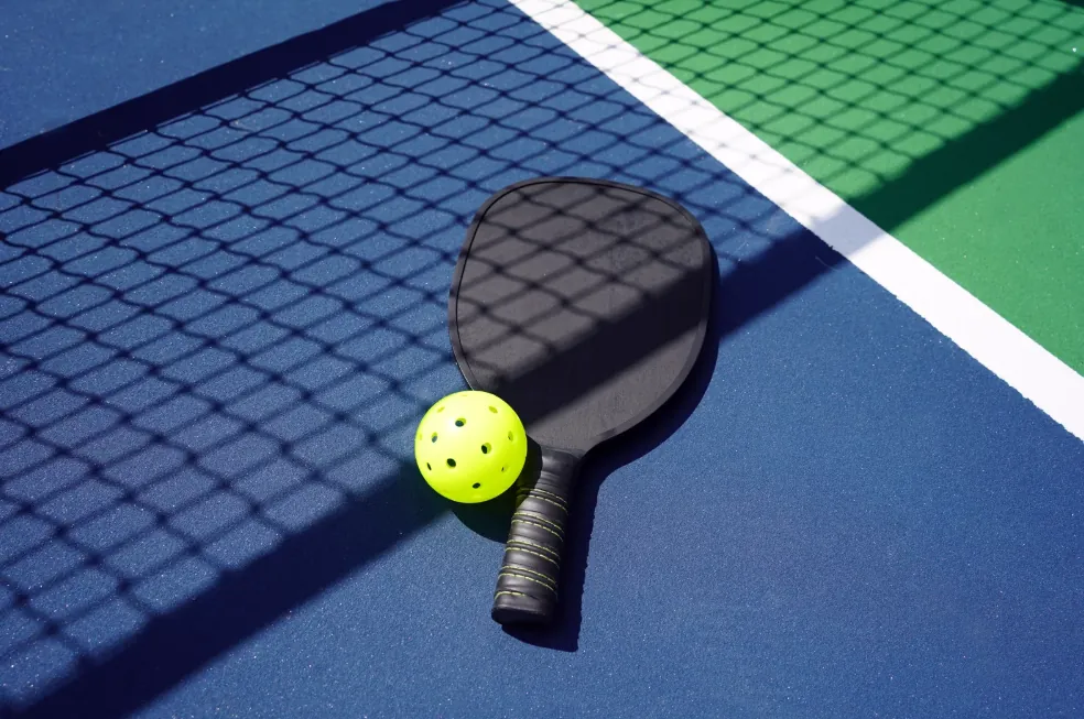 Pickleball paddle and ball on a court