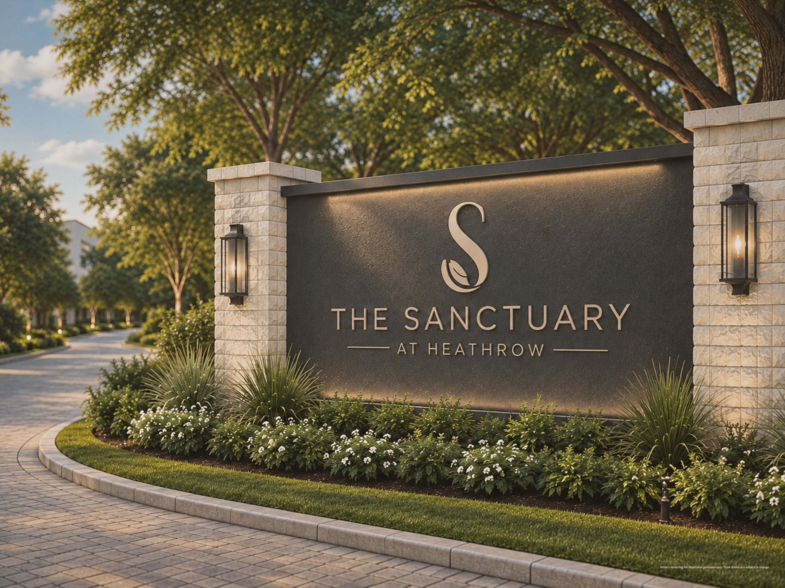 Entrance sign for The Sanctuary at Heathrow featuring a large dark plaque with the logo and name, flanked by two stone pillars each holding a lit lantern, surrounded by landscaping with green plants and white flowers alongside a curved paved driveway lined with trees in soft evening light.