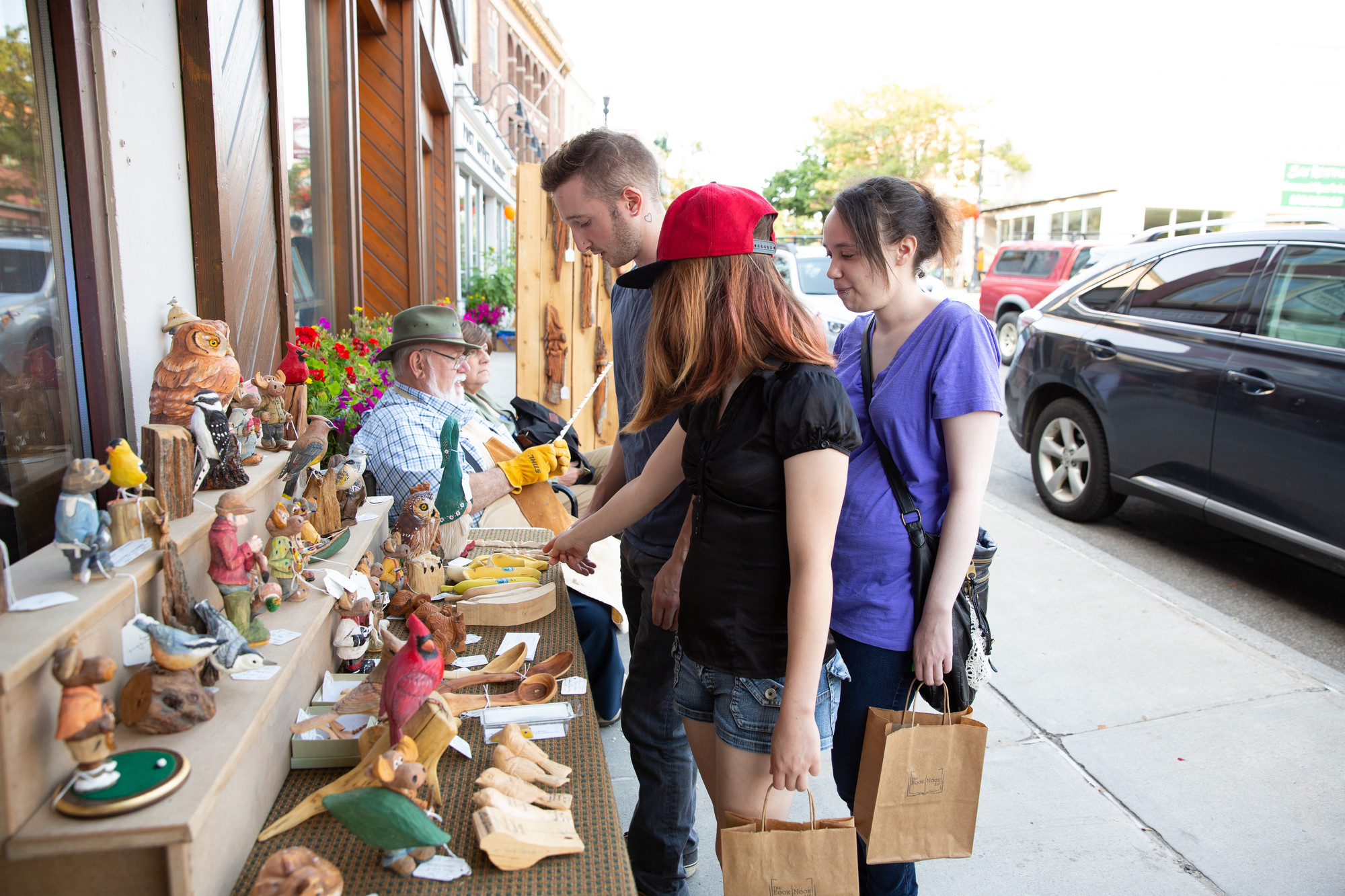 Three young people browse an artist's work during an Art Walk in Saranac Lake