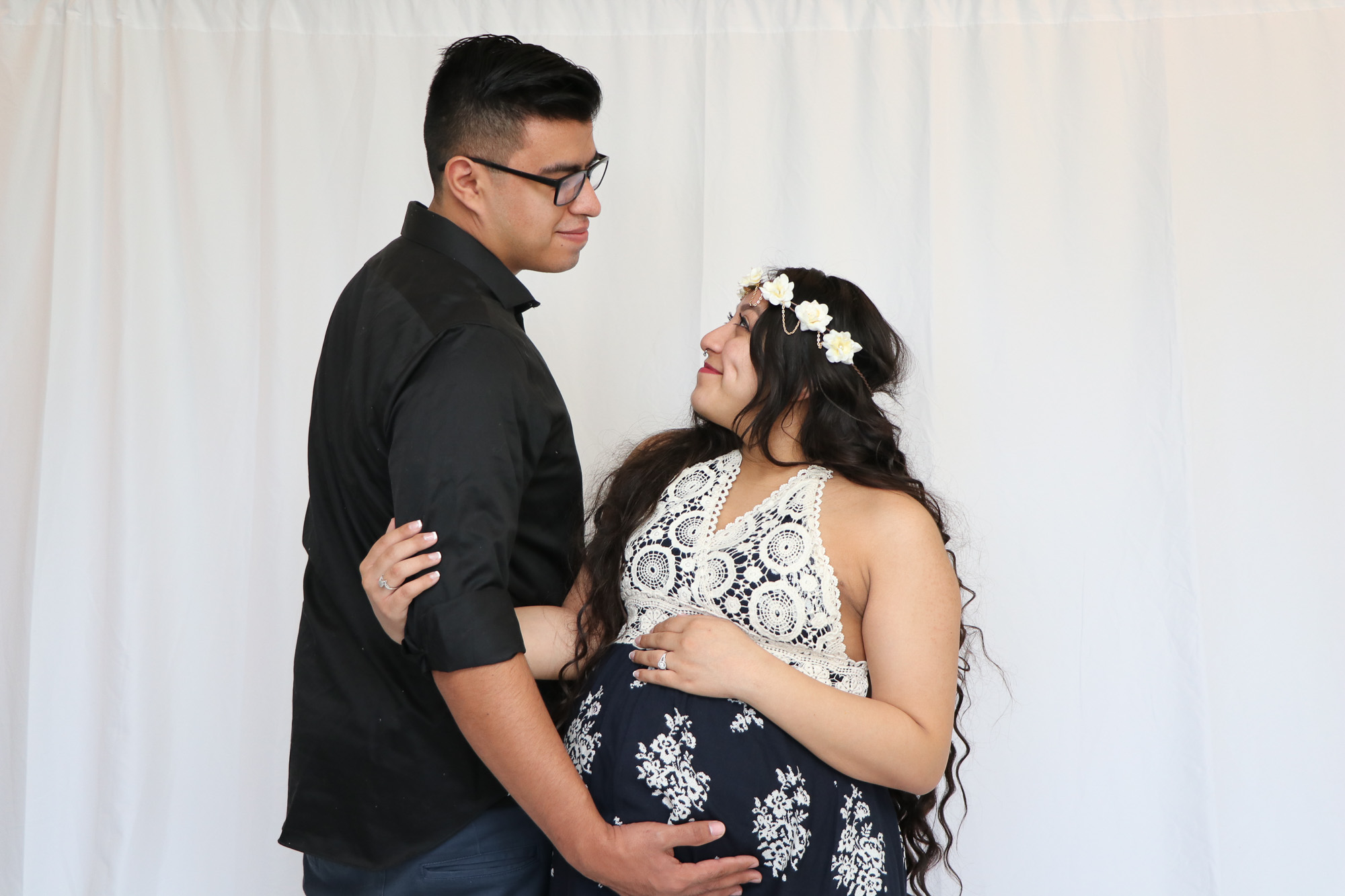 Studio maternity portrait of a couple against a white backdrop