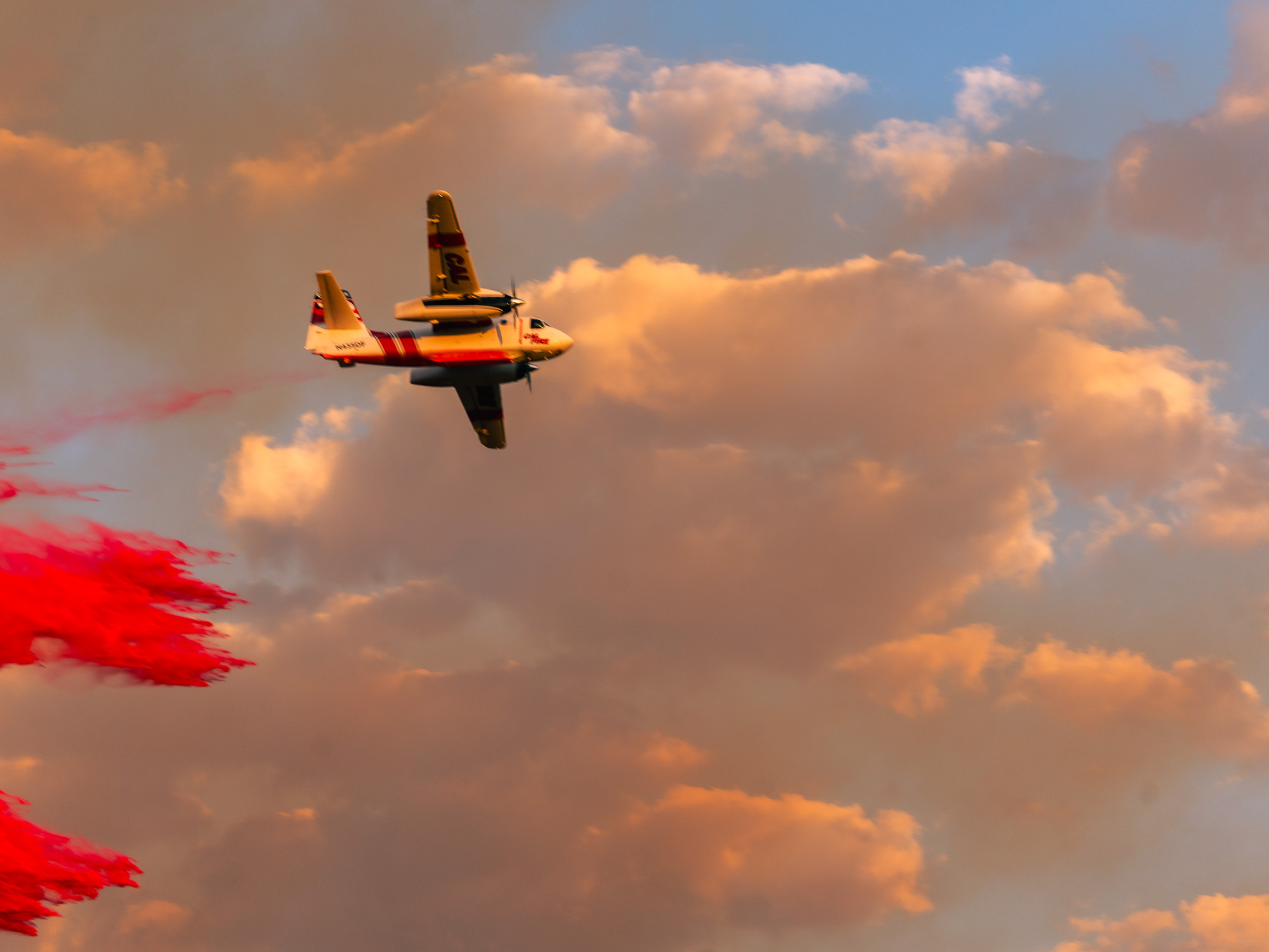 Firefighting plane dropping retardant over a wildfire