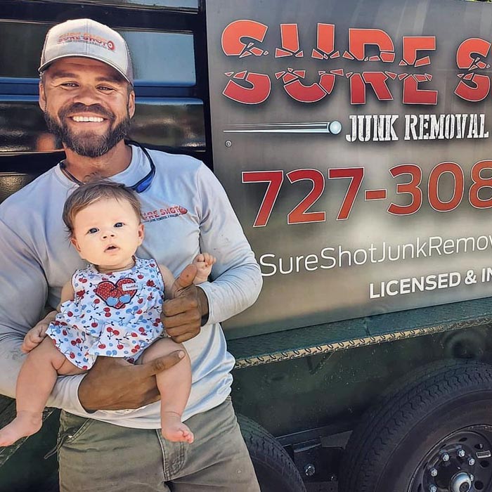 Then: Christopher holding his infant daughter beside the original Sure Shot Junk Removal truck.