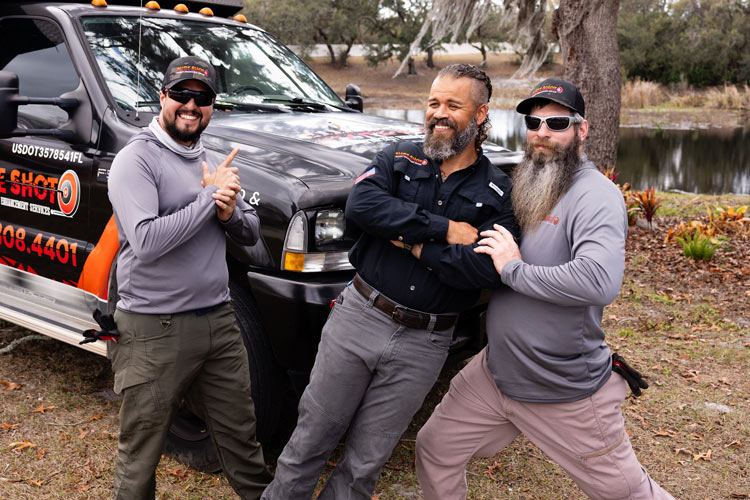 Christopher, Julio, and Mark of Sure Shot Property Enhancement Services standing together beside a branded company truck