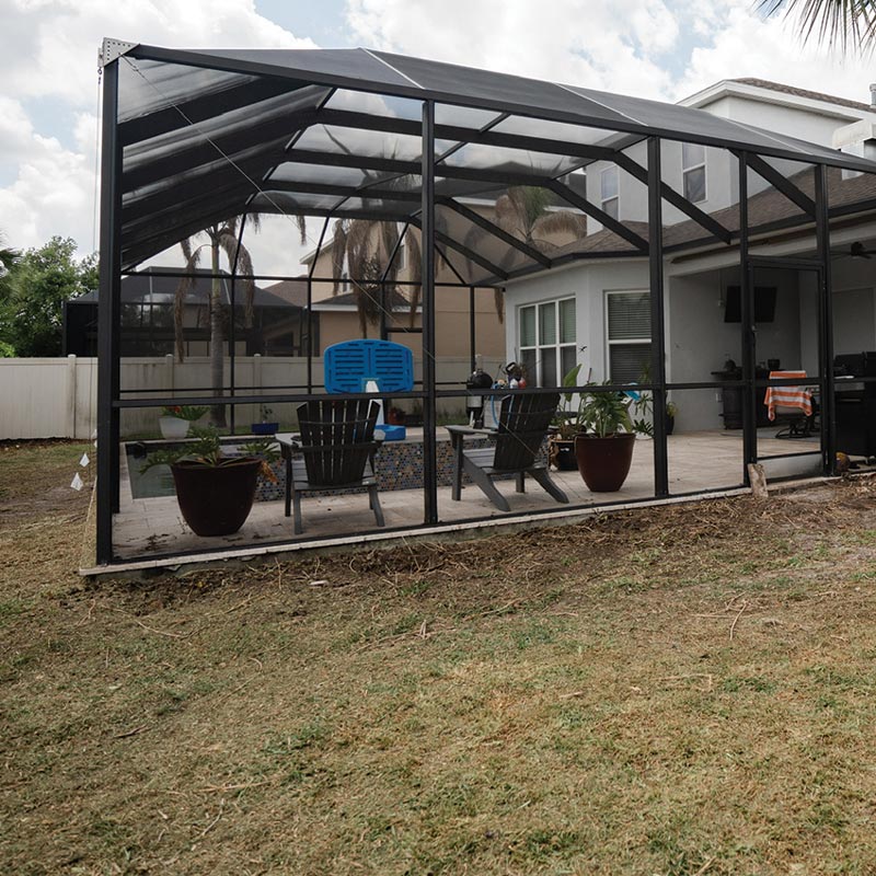 Backyard before landscaping, showing a screened patio surrounded by bare lawn and minimal planting.