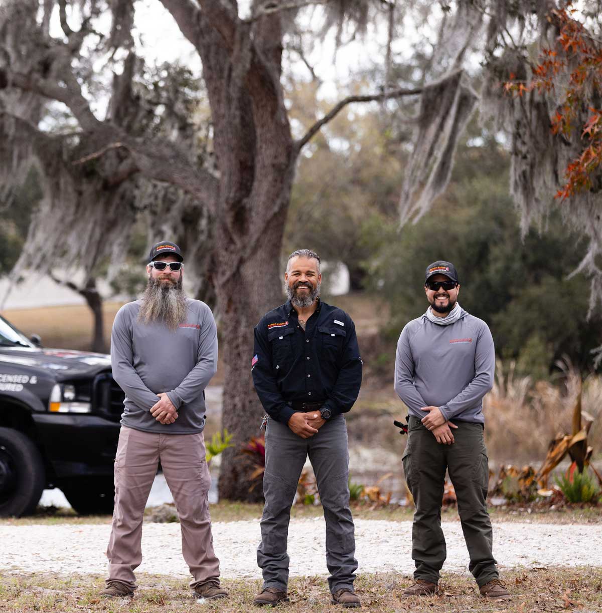 Christopher, Mark, and Julio of Sure Shot Property Enhancement Services standing outdoors beside a company vehicle