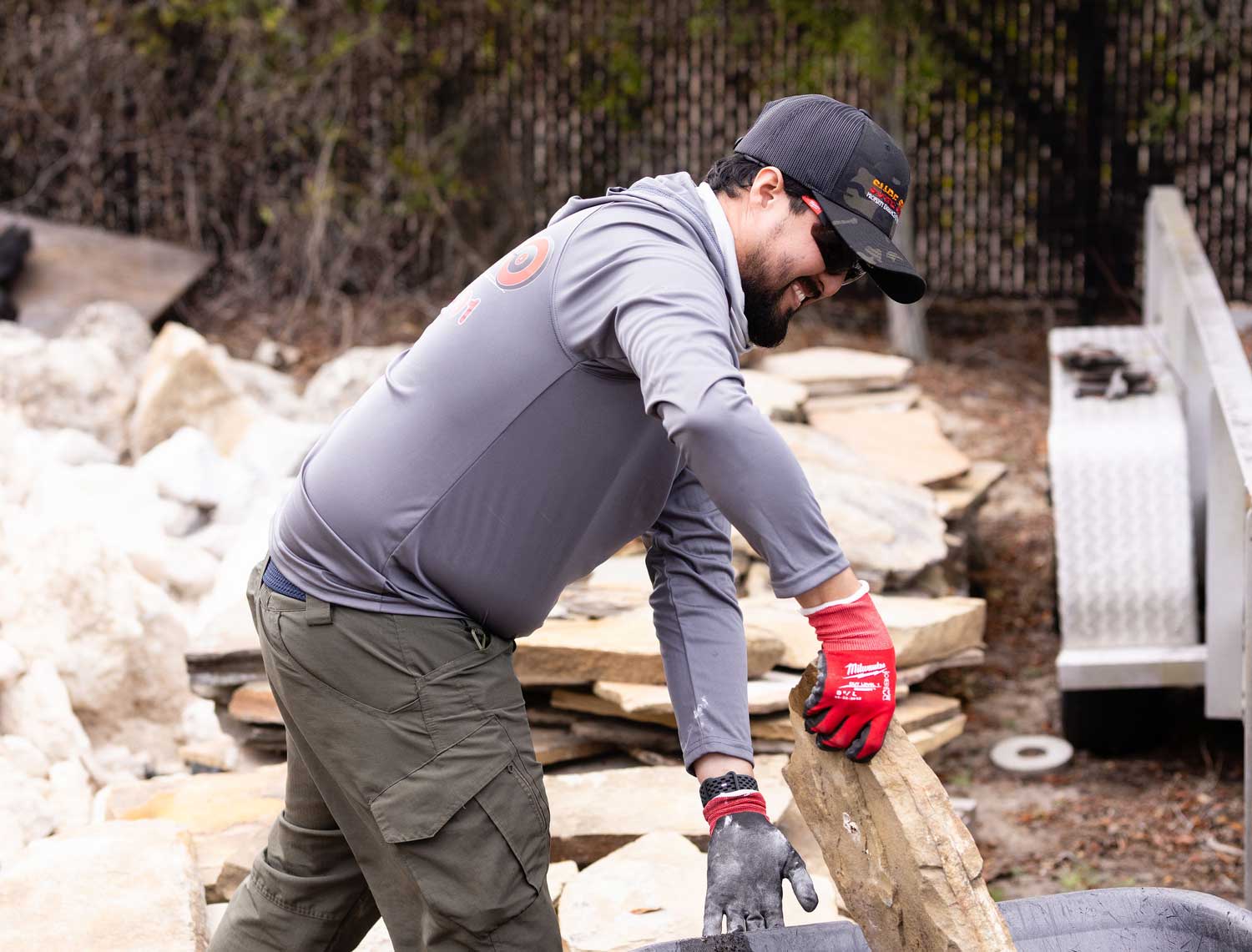Sure Shot team member handling natural stone during a landscape installation project