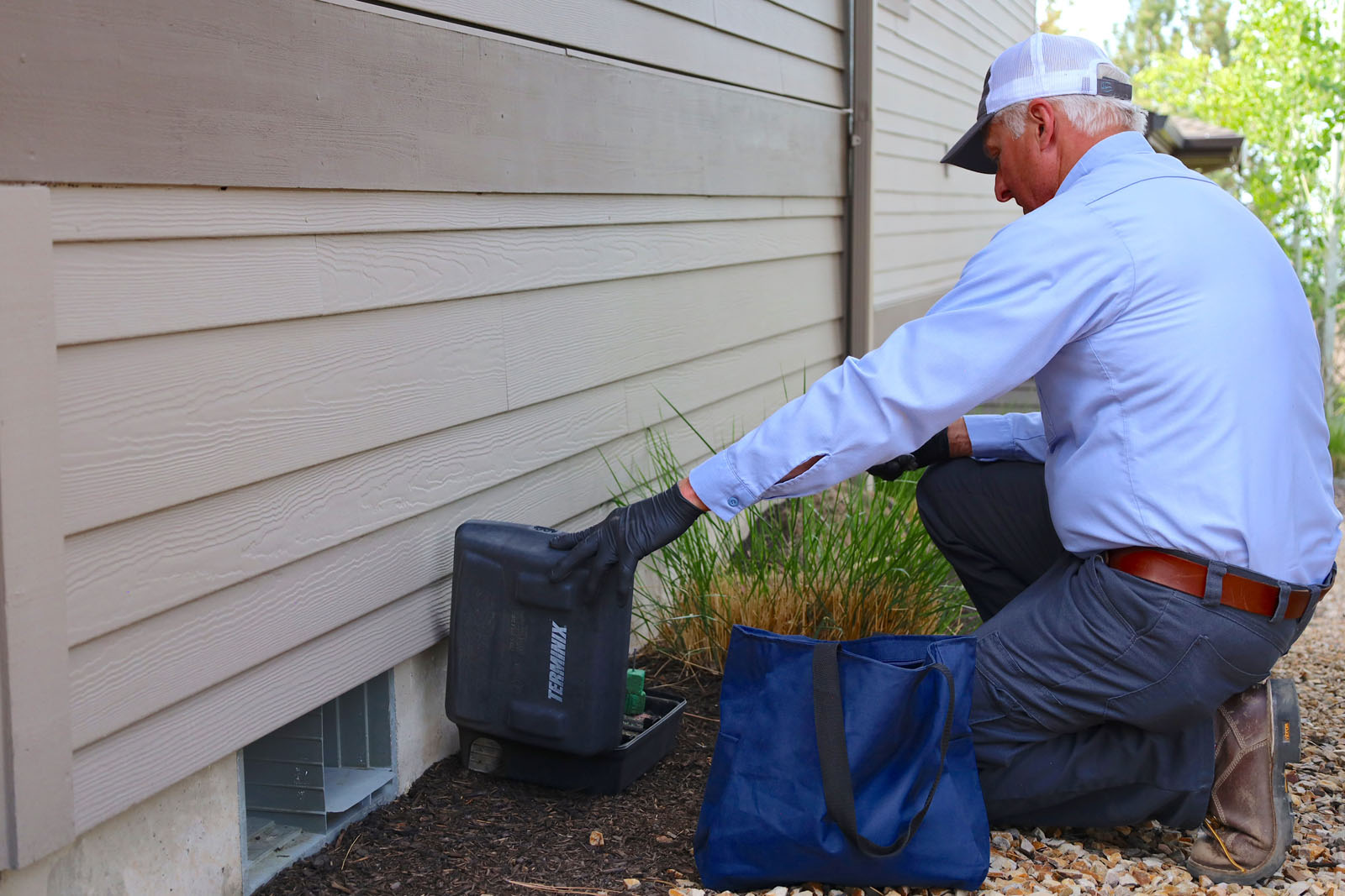 A Terminix technician is setting a mouse trap with bait.