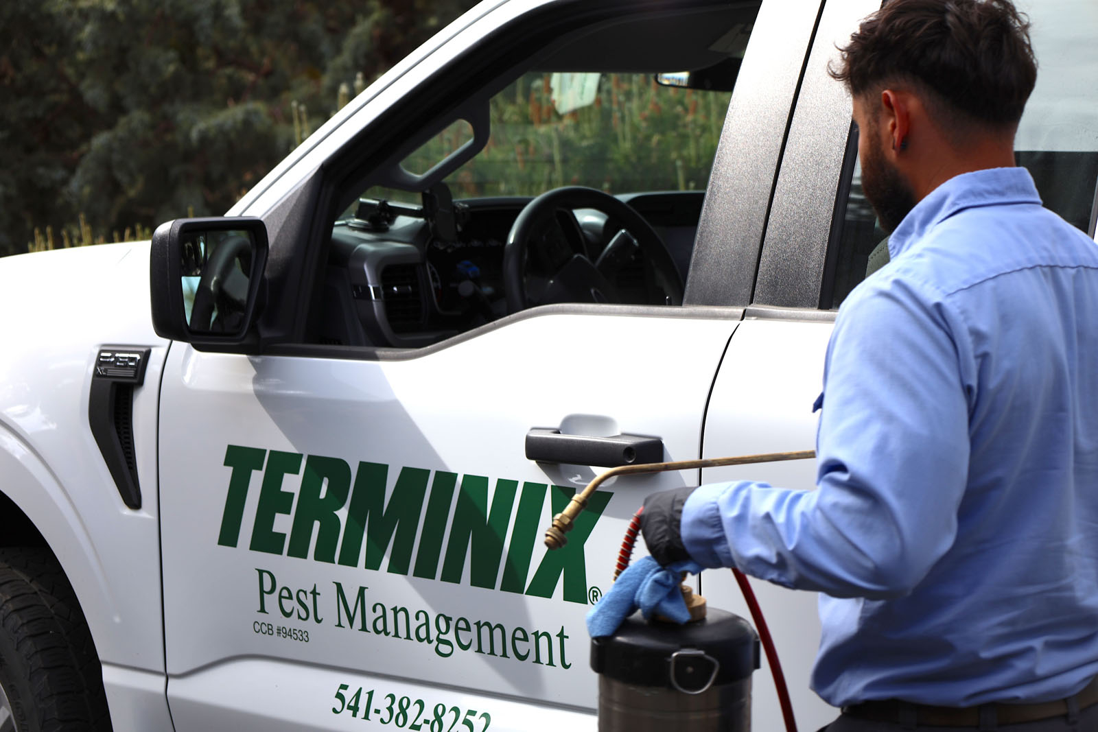 A Terminix technician working near a Terminix company truck.