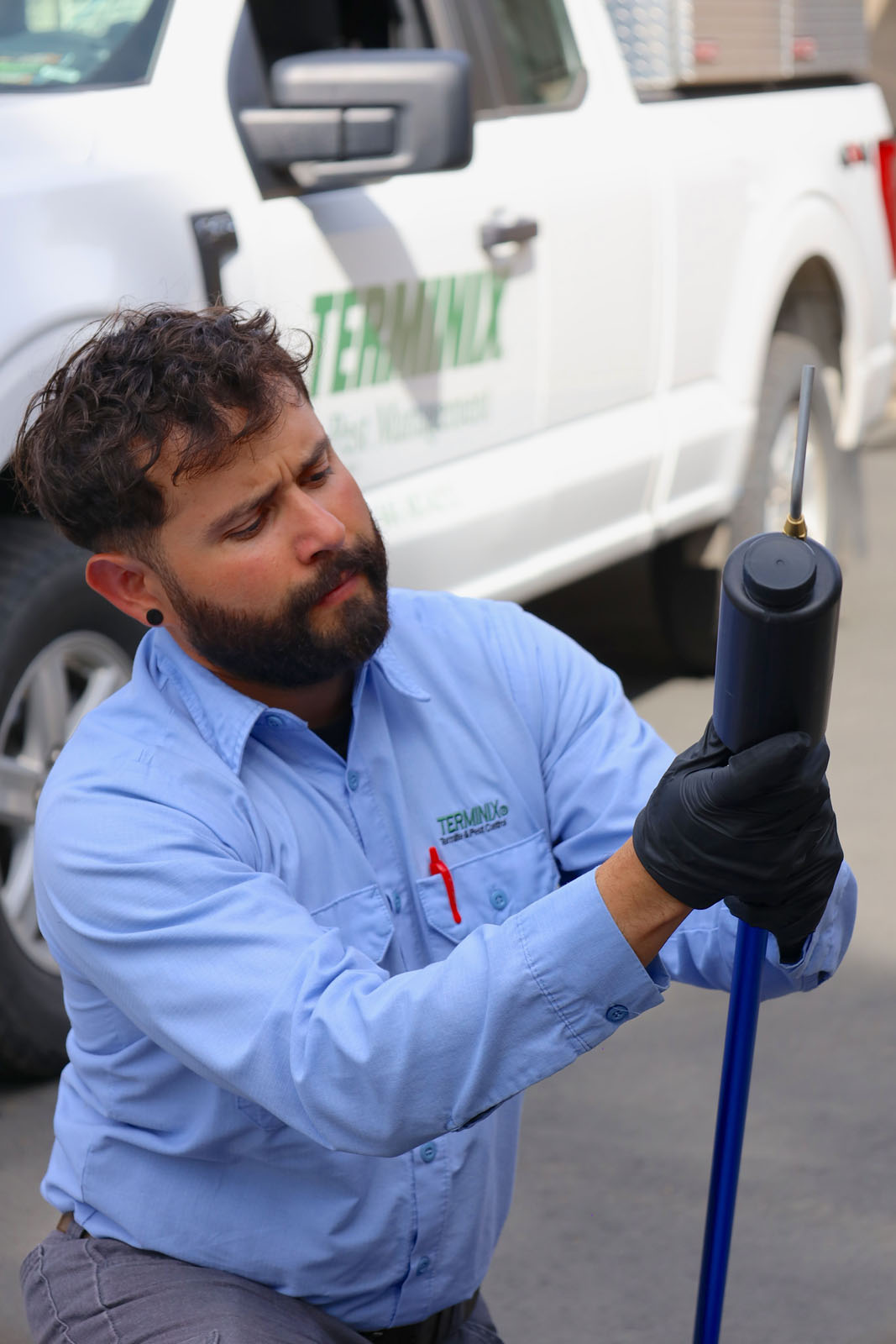 A Terminix team member is working with an insecticide sprayer.
