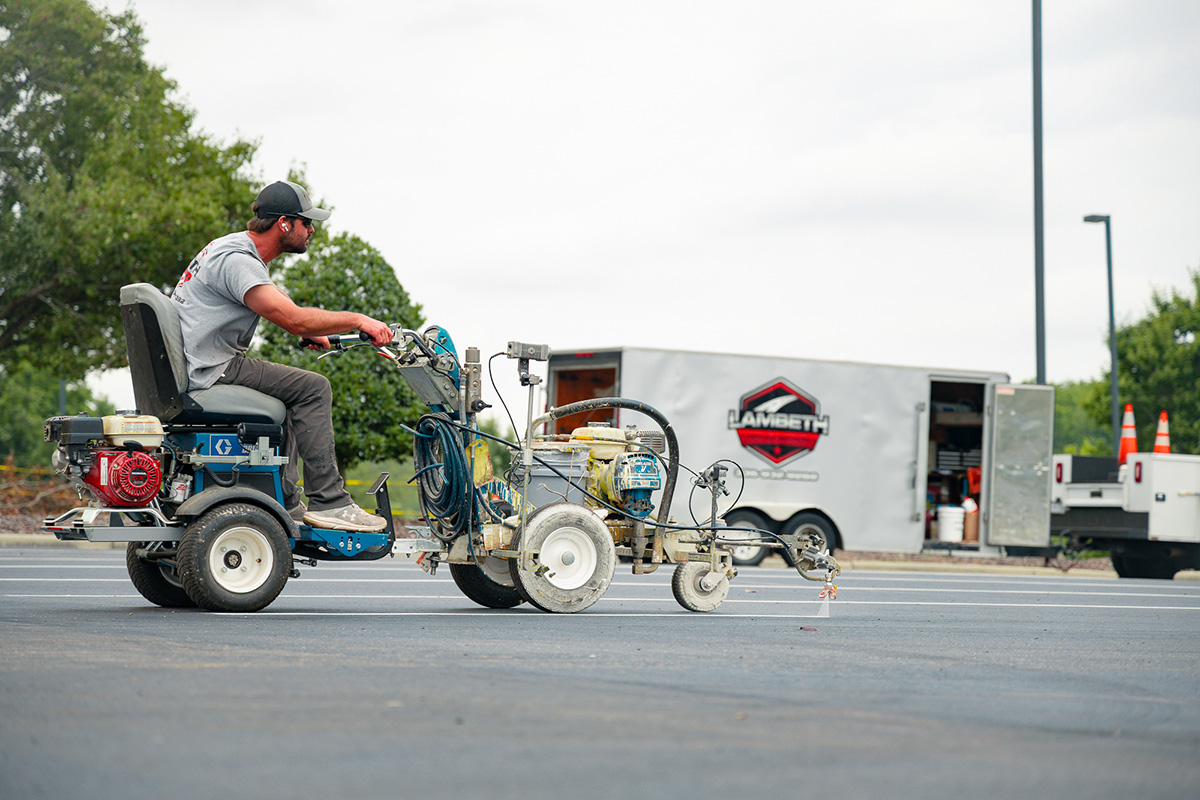 Lambeth Asphalt crew member operating a ride-on line striper painting fresh parking lot stripes at Grandover Resort, Greensboro NC