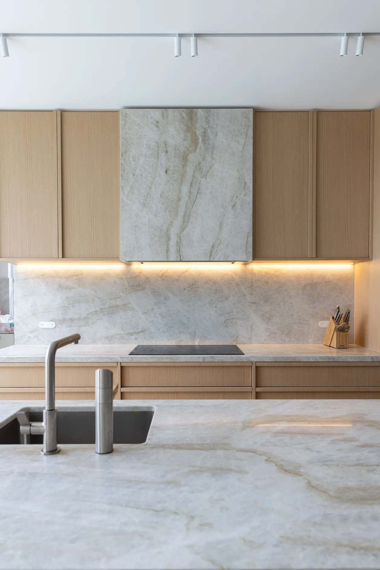 Kitchen cabinetry with stone backsplash and under cabinet lighting in Kogarah Bay Sydney