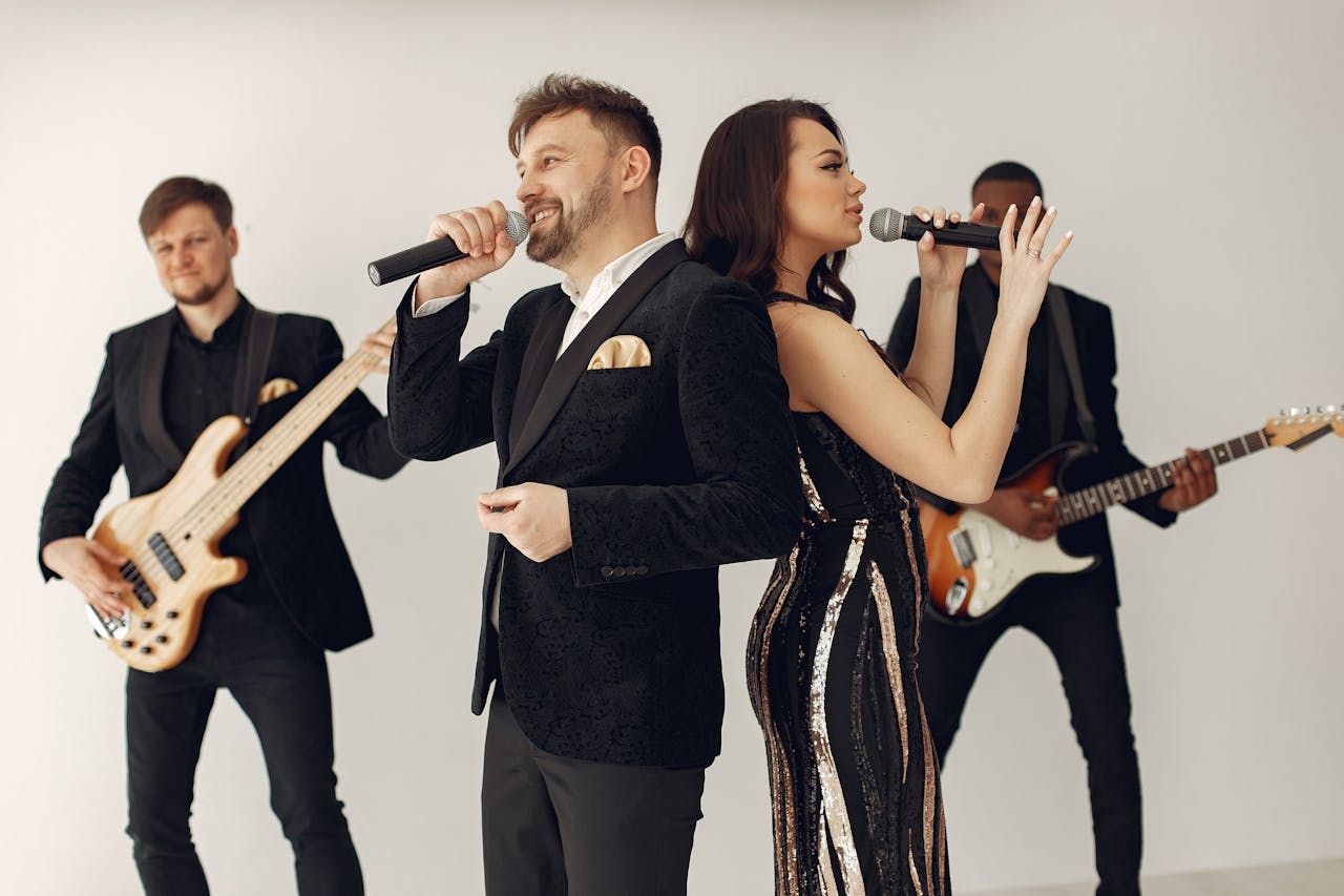 A band performing. Band consists of two singers, a lead guitar player, and a bass player.