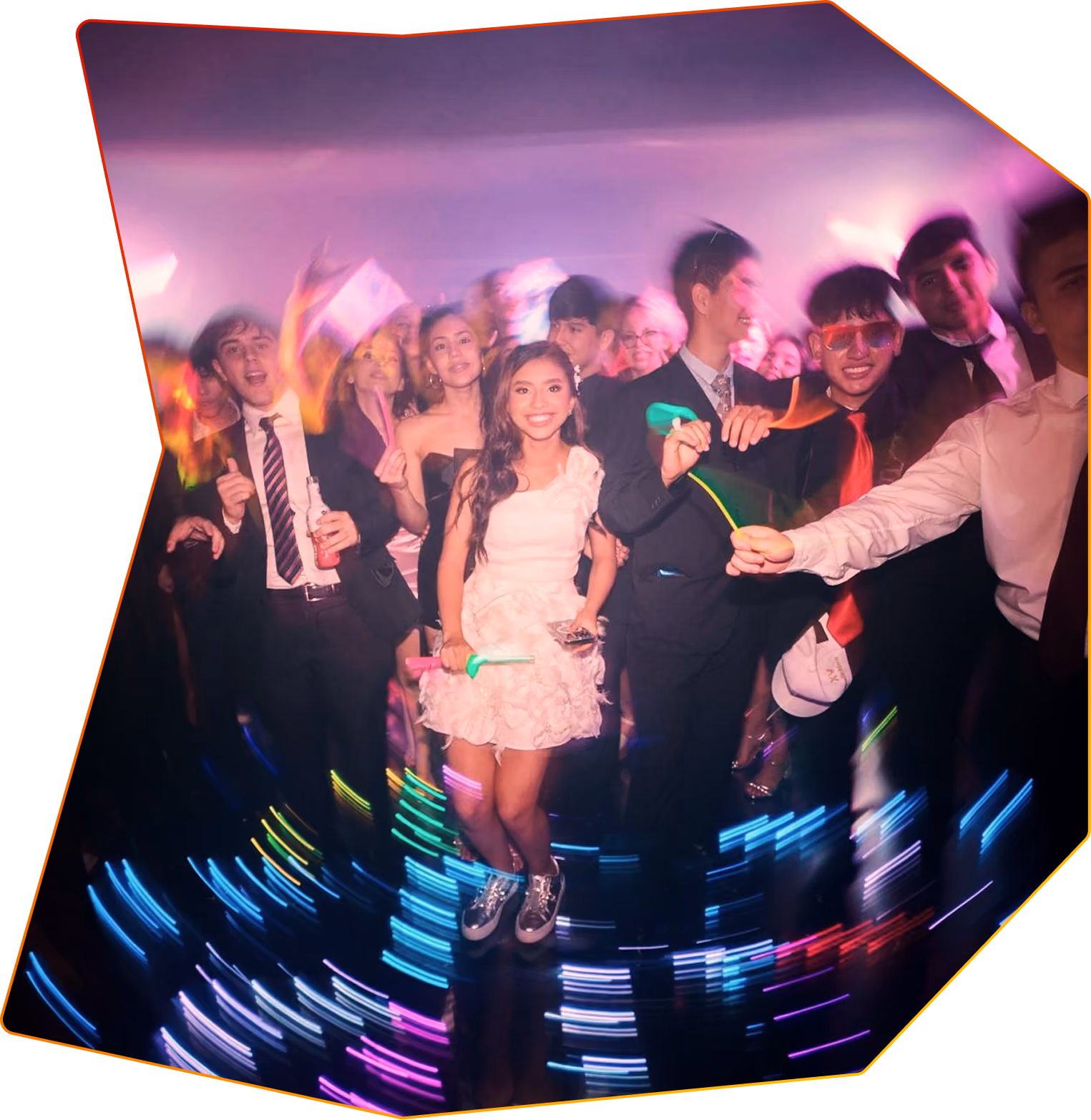A school prom with students dressed in formal clothing dancing in a glowing room.