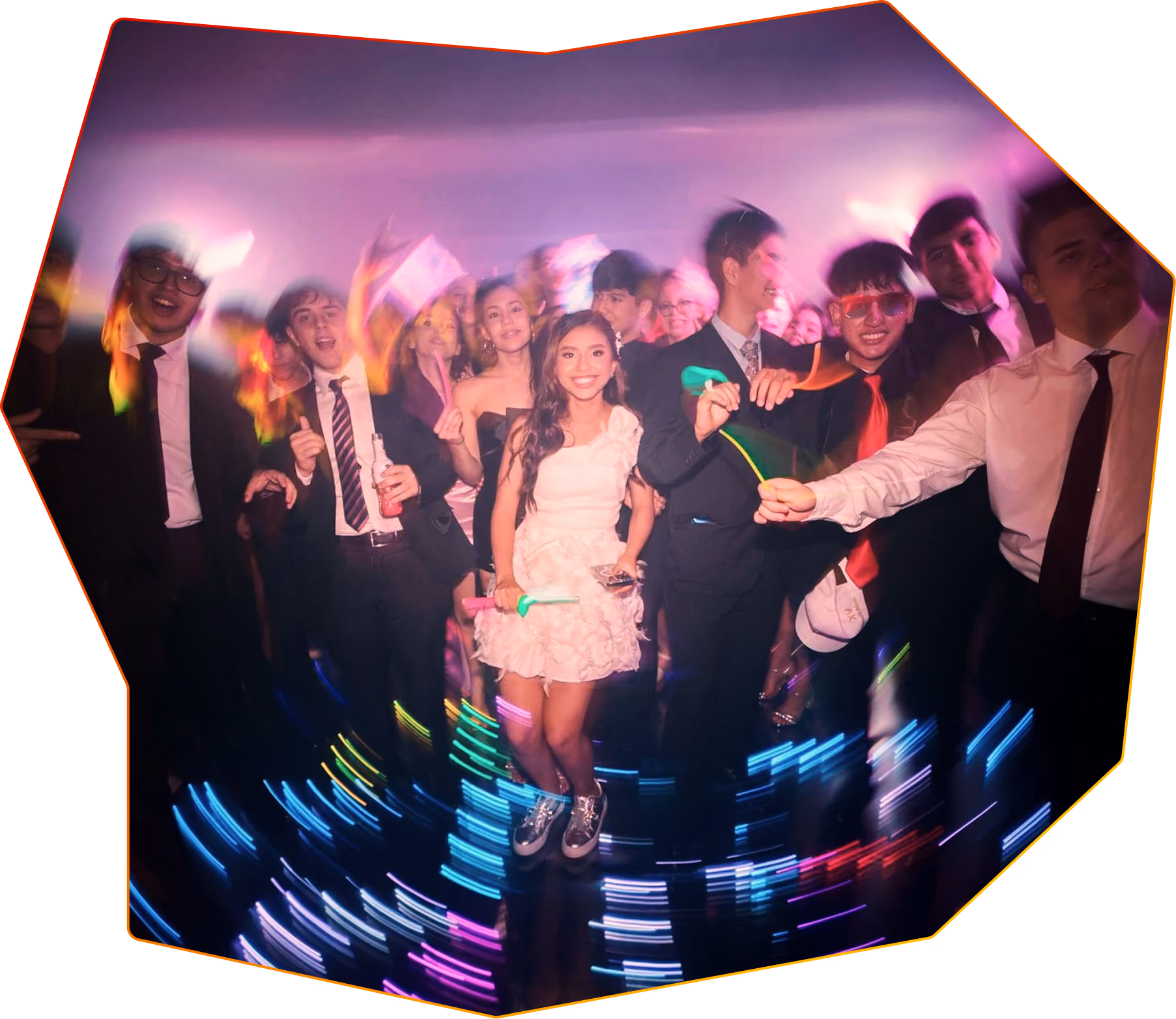 A school prom with students dressed in formal clothing dancing in a glowing room.
