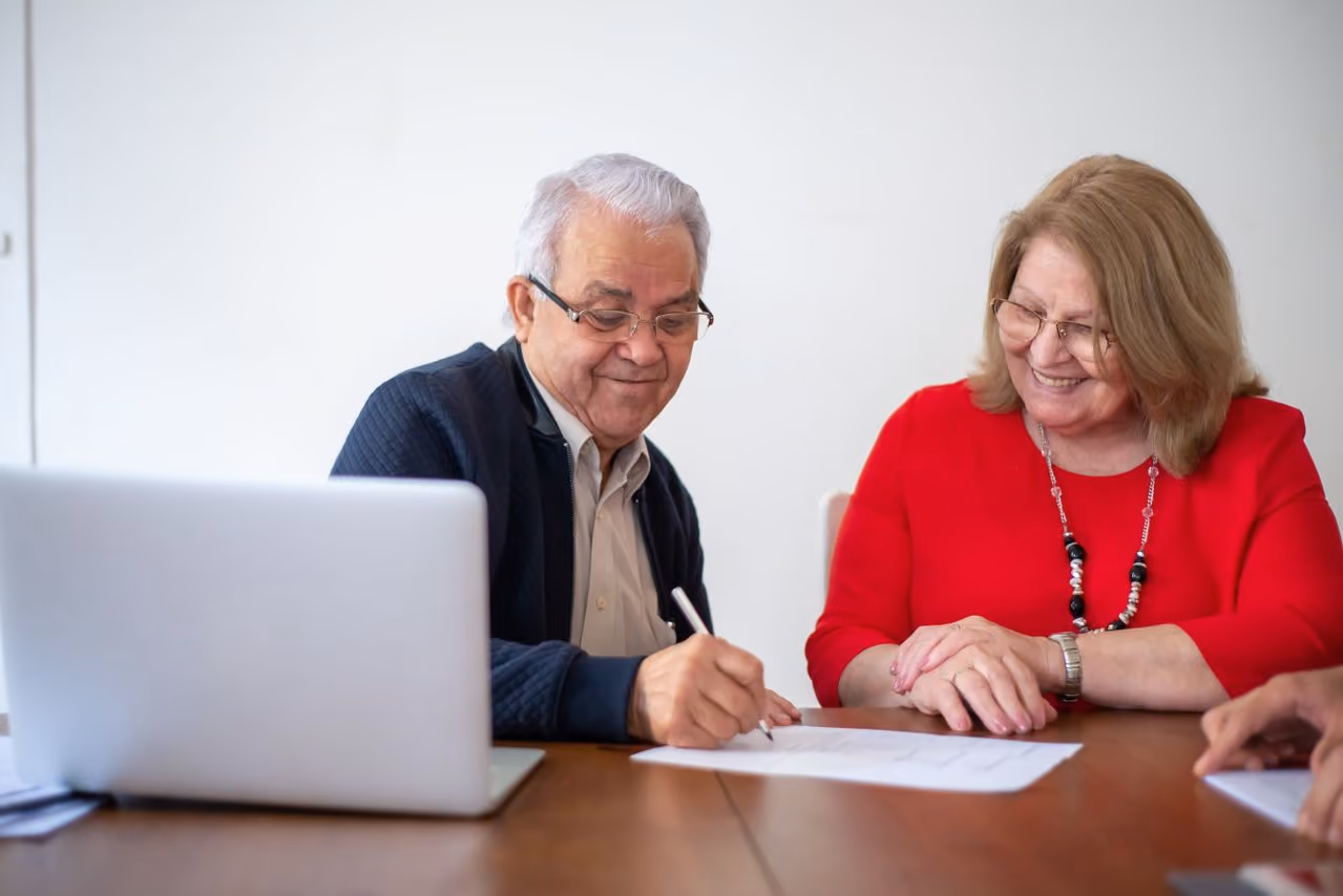 An elderly couple signing legal documents