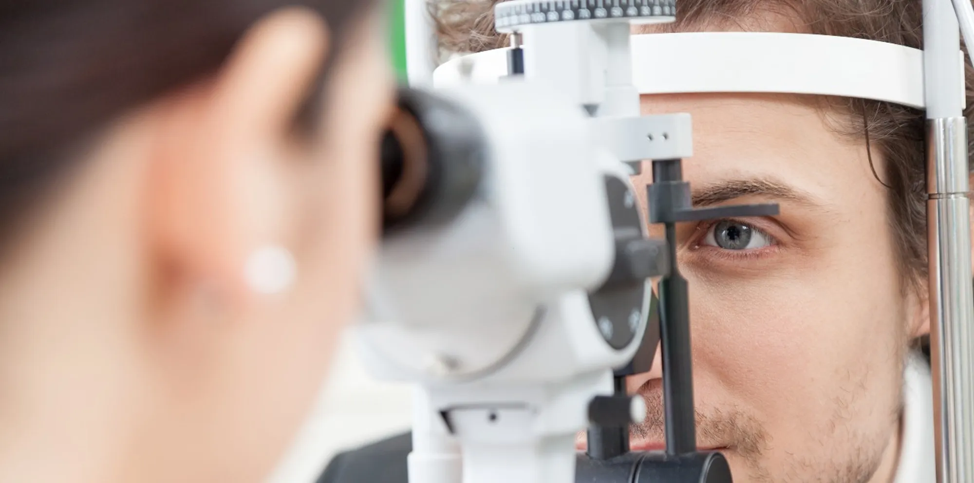 Optometrist examining a man's eye with a slit lamp during an eye exam.