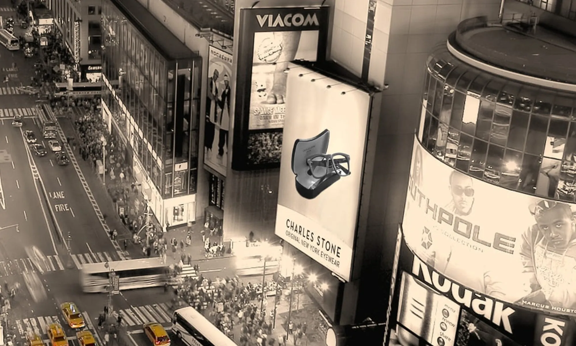 Aerial sepia view of Times Square with a Charles Stone eyewear billboard among city ads and yellow taxis below