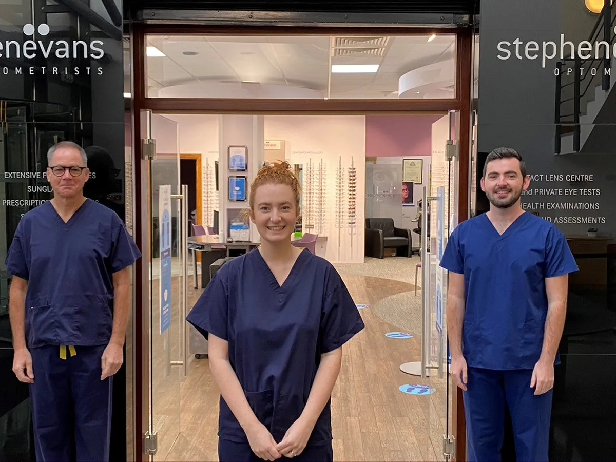 Three optometry staff in navy scrubs standing at the entrance of Stephen Evans Optometrists