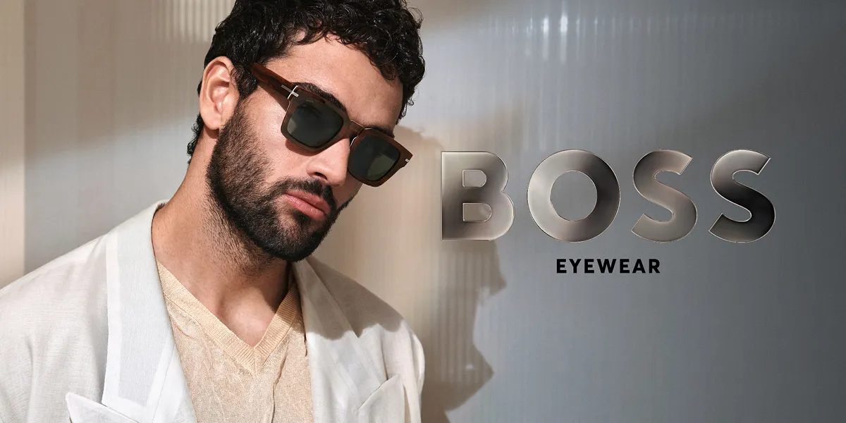 Man in beige clothing wearing dark sunglasses beside the text BOSS EYEWEAR on a gray background.