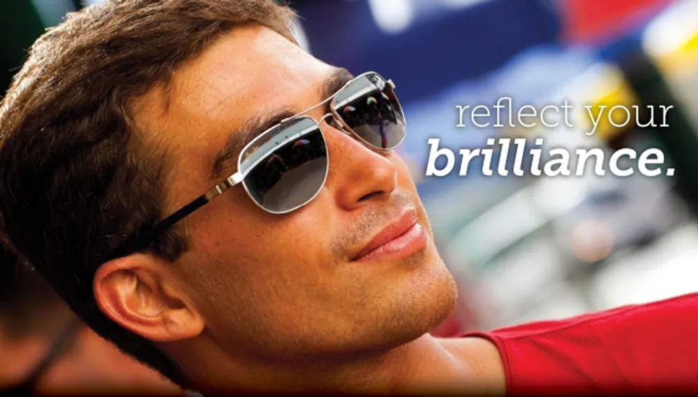 Man wearing reflective sunglasses looking up with a blurred colorful background and text 'reflect your brilliance.'