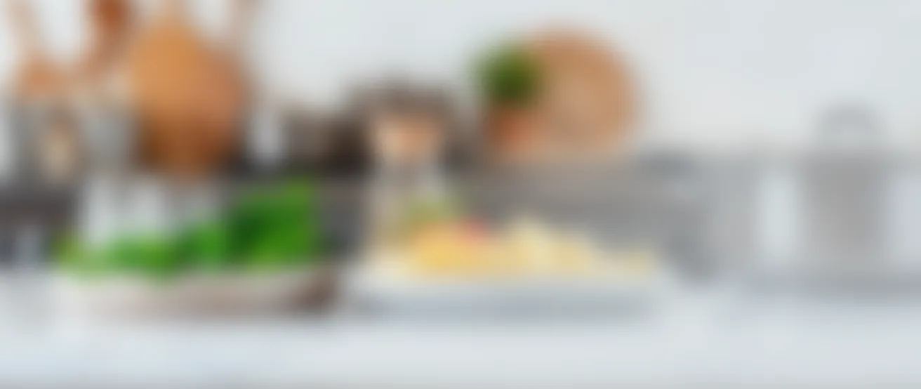 Blurred kitchen countertop with plates of food and cooking utensils in the background.