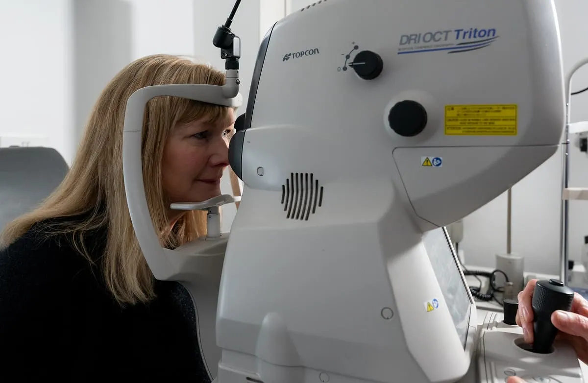 Woman undergoing an eye exam using a Topcon DRI OCT Triton imaging device.
