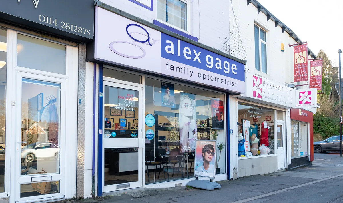 Street view of Alex Gage family opticians shop with purple signage and storefront window displaying eyewear.