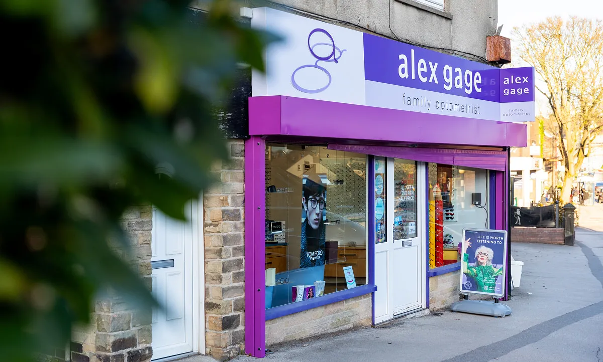 Street view of Alex Gage family opticians shop with purple signage and storefront window displaying eyewear.