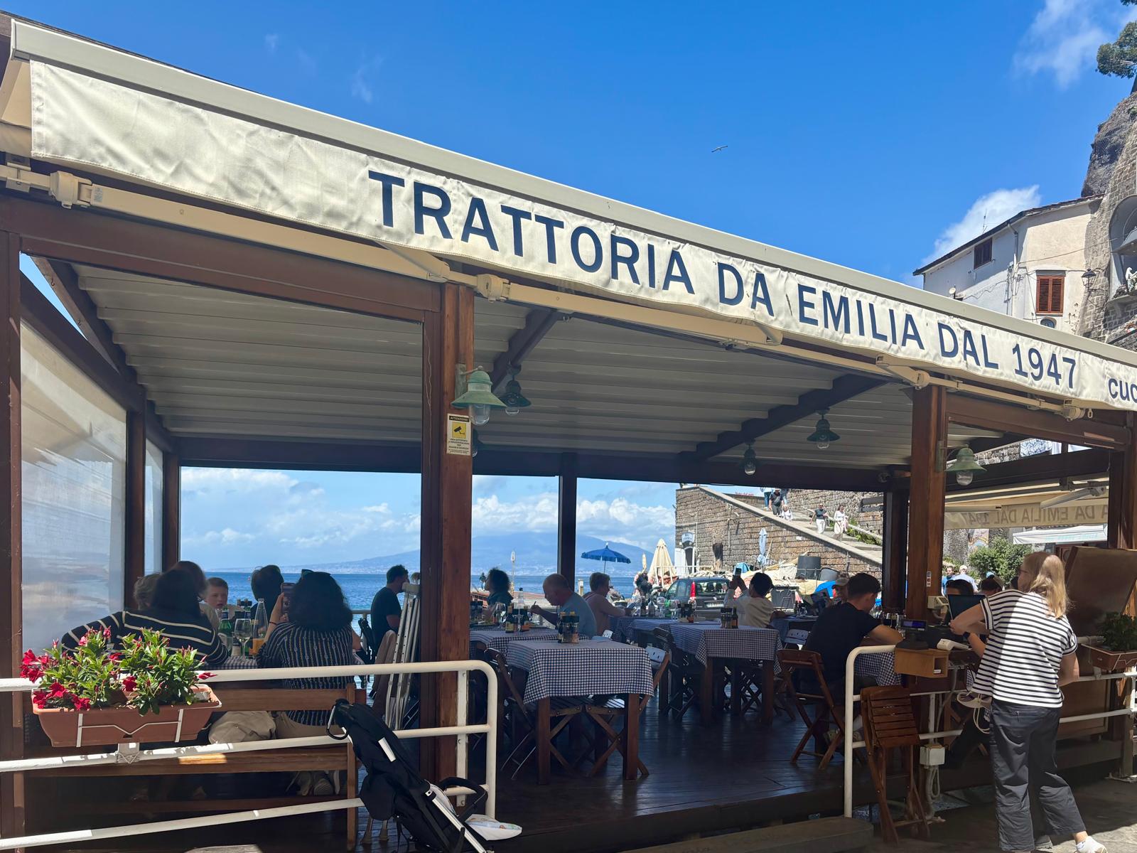 Outdoor terrace of Albergo Lorelei restaurant overlooking blue sea and distant mountain.