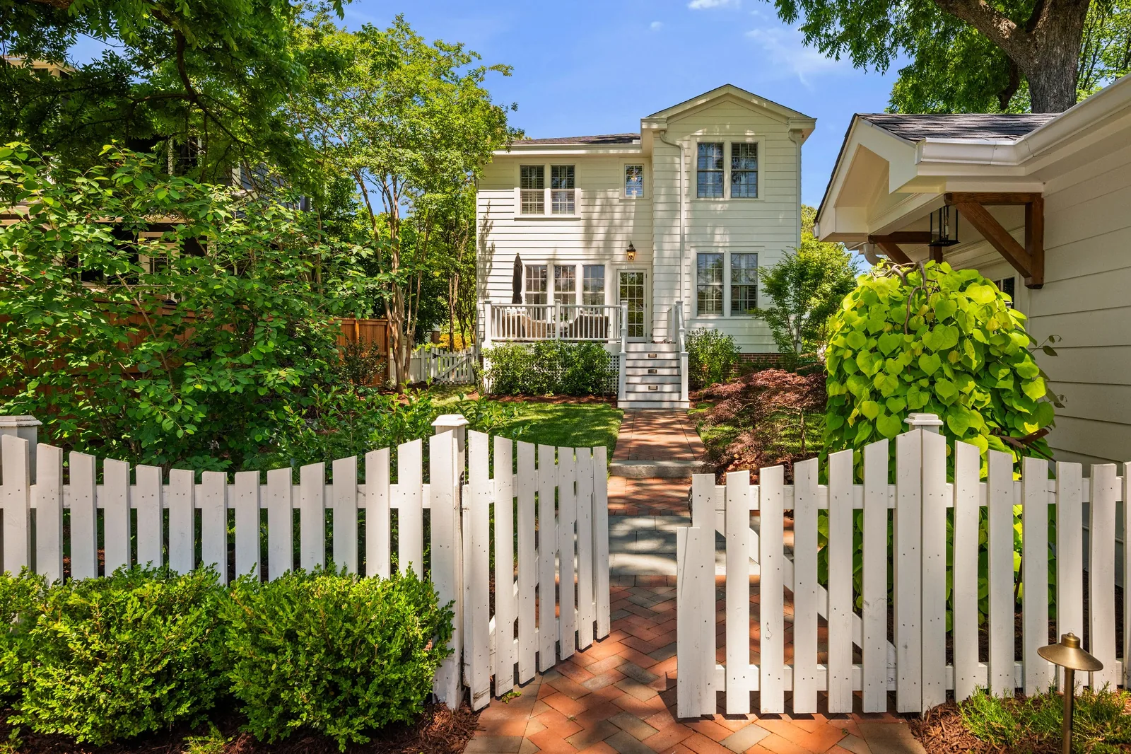 Garden-side exterior with a white picket fence, brick path, and mature landscaping at a Durham, North Carolina home.
