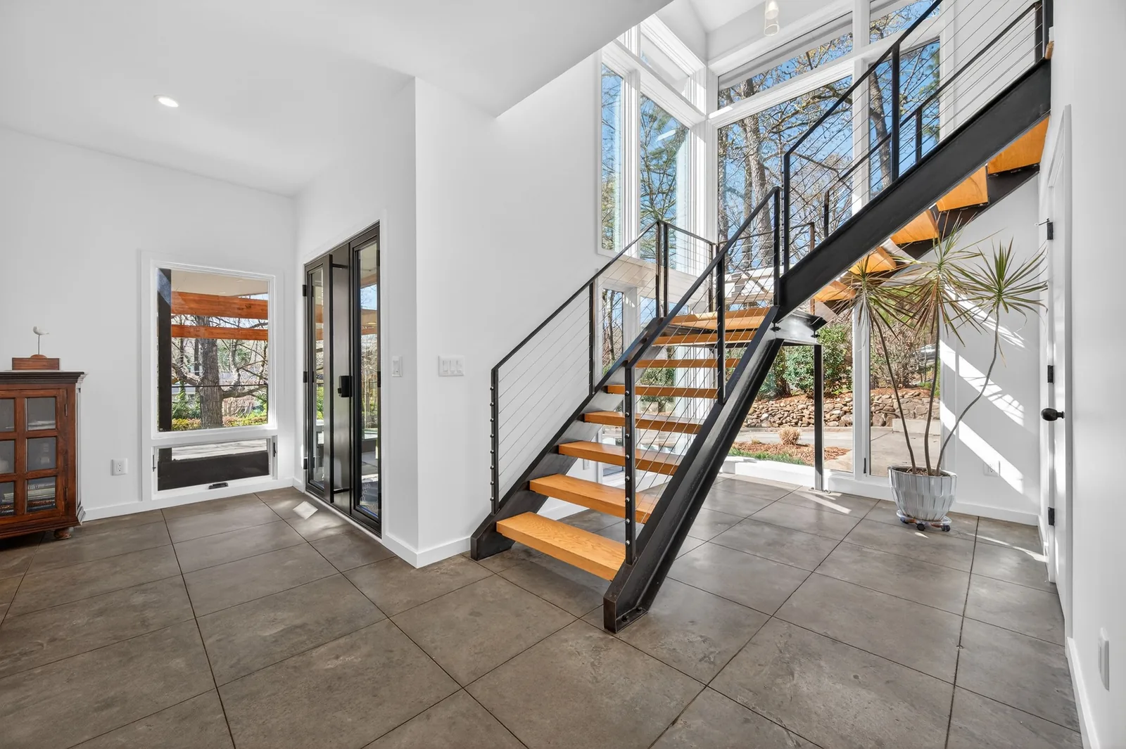 Modern open-riser staircase with steel framing and expansive windows in a Chapel Hill, North Carolina residence.