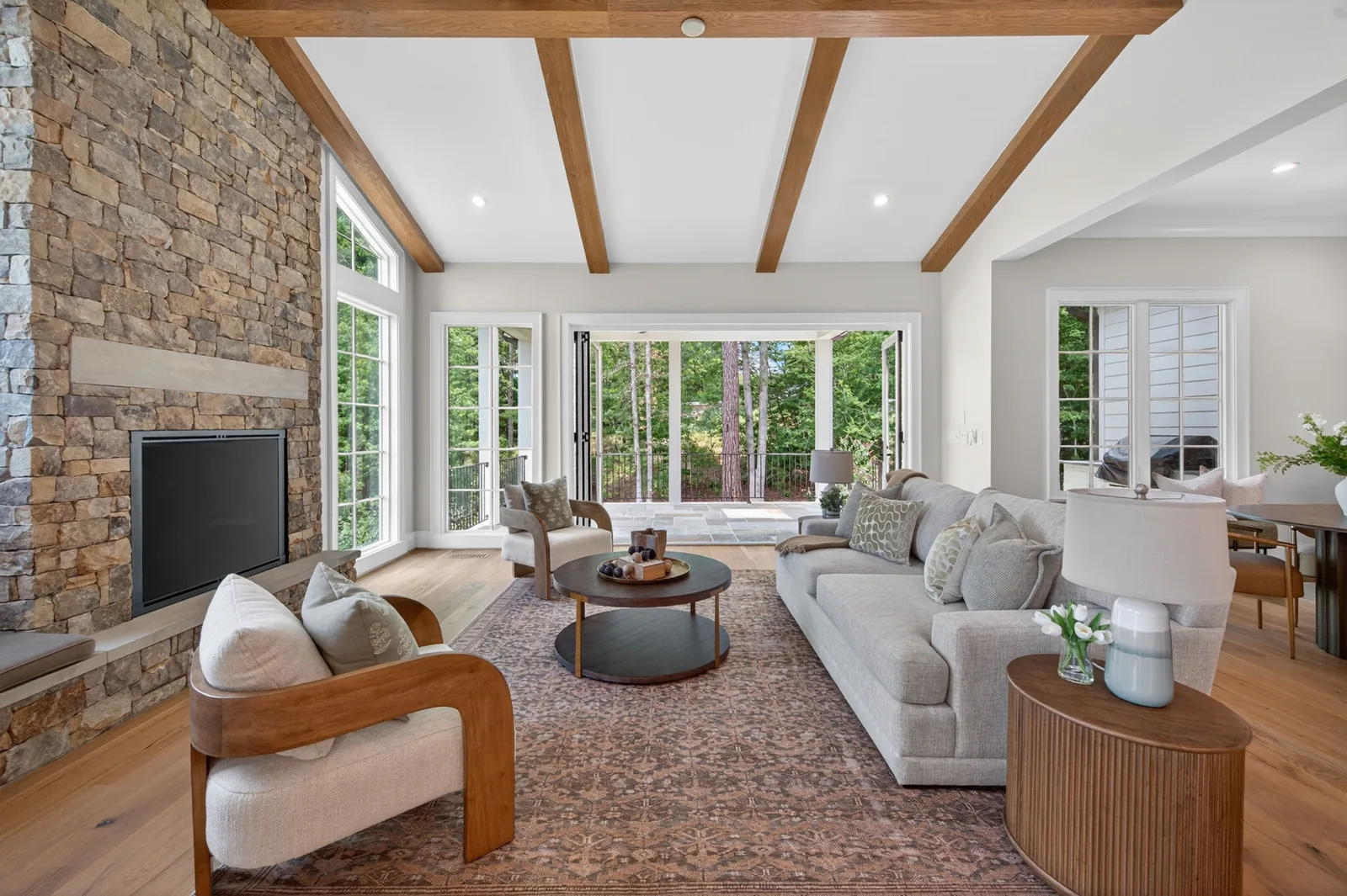 Bright living room with stone fireplace and wood ceiling beams in Garner, NC