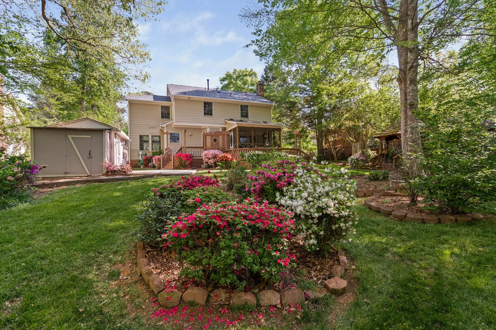 Landscaped backyard with mature trees and flowering garden in Garner, North Carolina