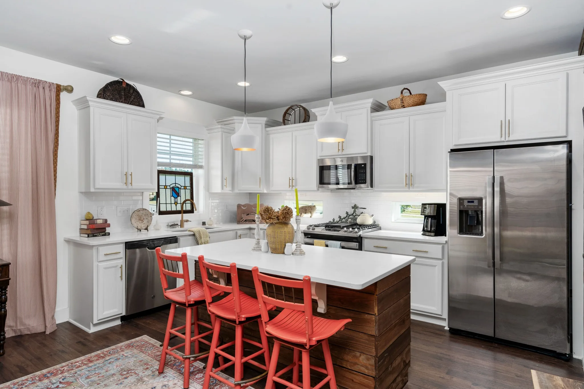 Modern kitchen with white cabinetry, wood island, and colorful bar stools in Pittsboro, North Carolina.
