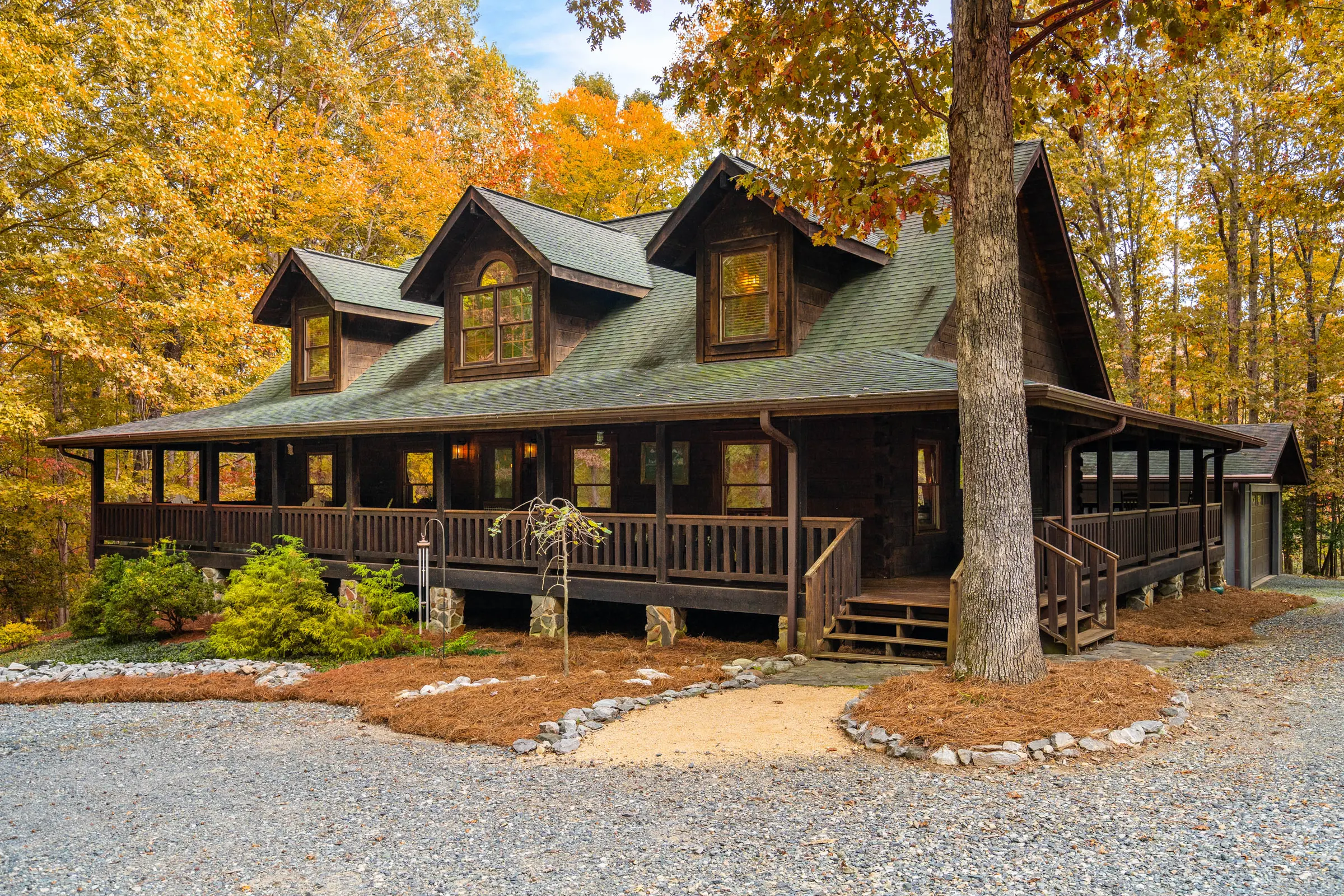 Wood-sided Hillsborough home with a wraparound porch amid autumn trees, photographed by Upper Echelon Visuals