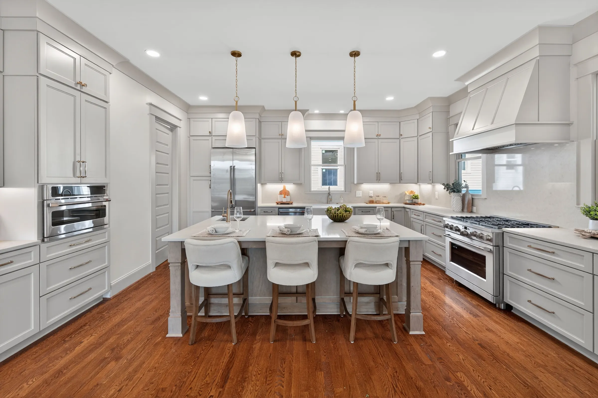 Bright Knightdale kitchen with a large island, upholstered stools, and white pendant lights, photographed by Upper Echelon Visuals