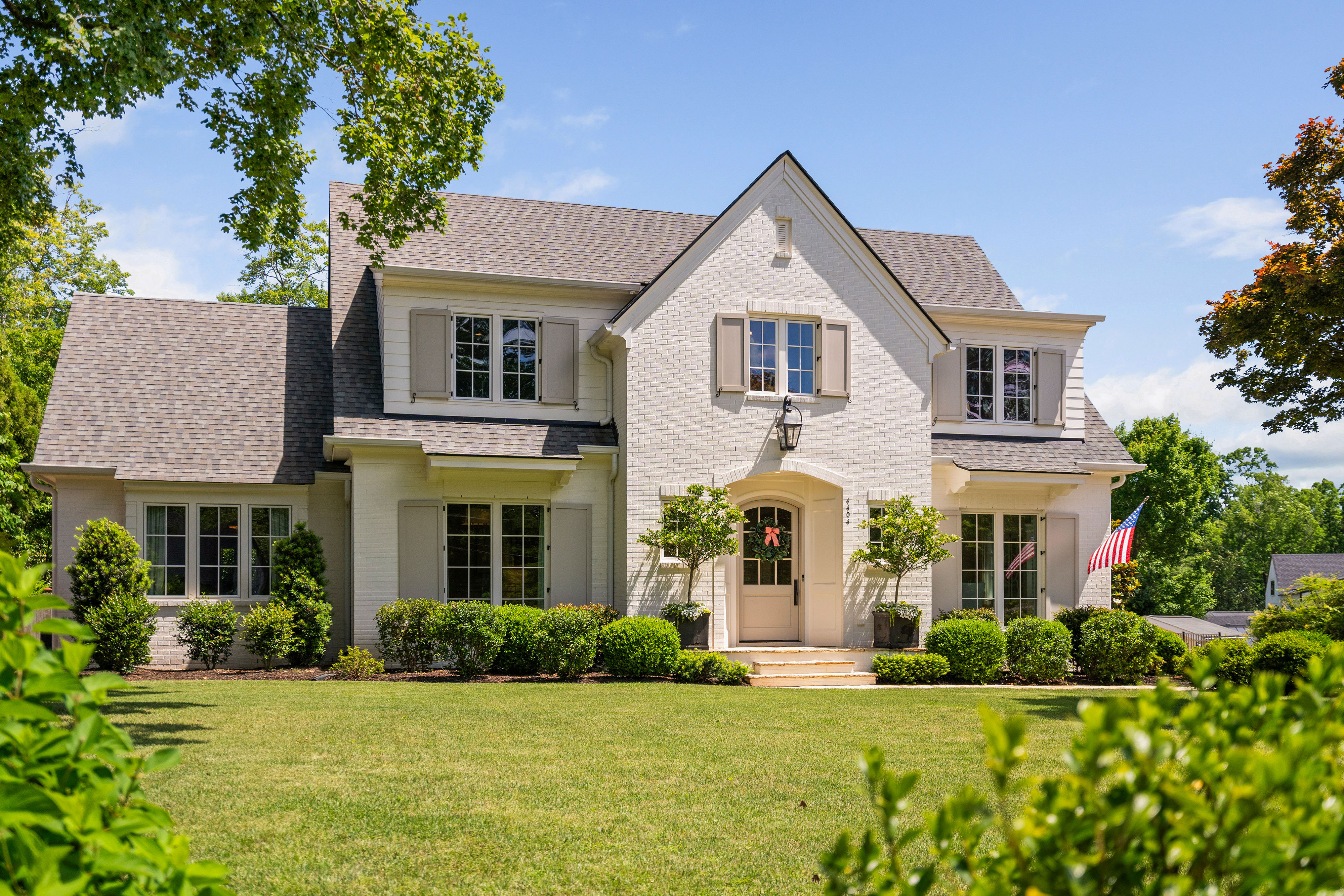 White brick Zebulon home with a central gable, pale shutters, and landscaped front garden, photographed by Upper Echelon Visuals