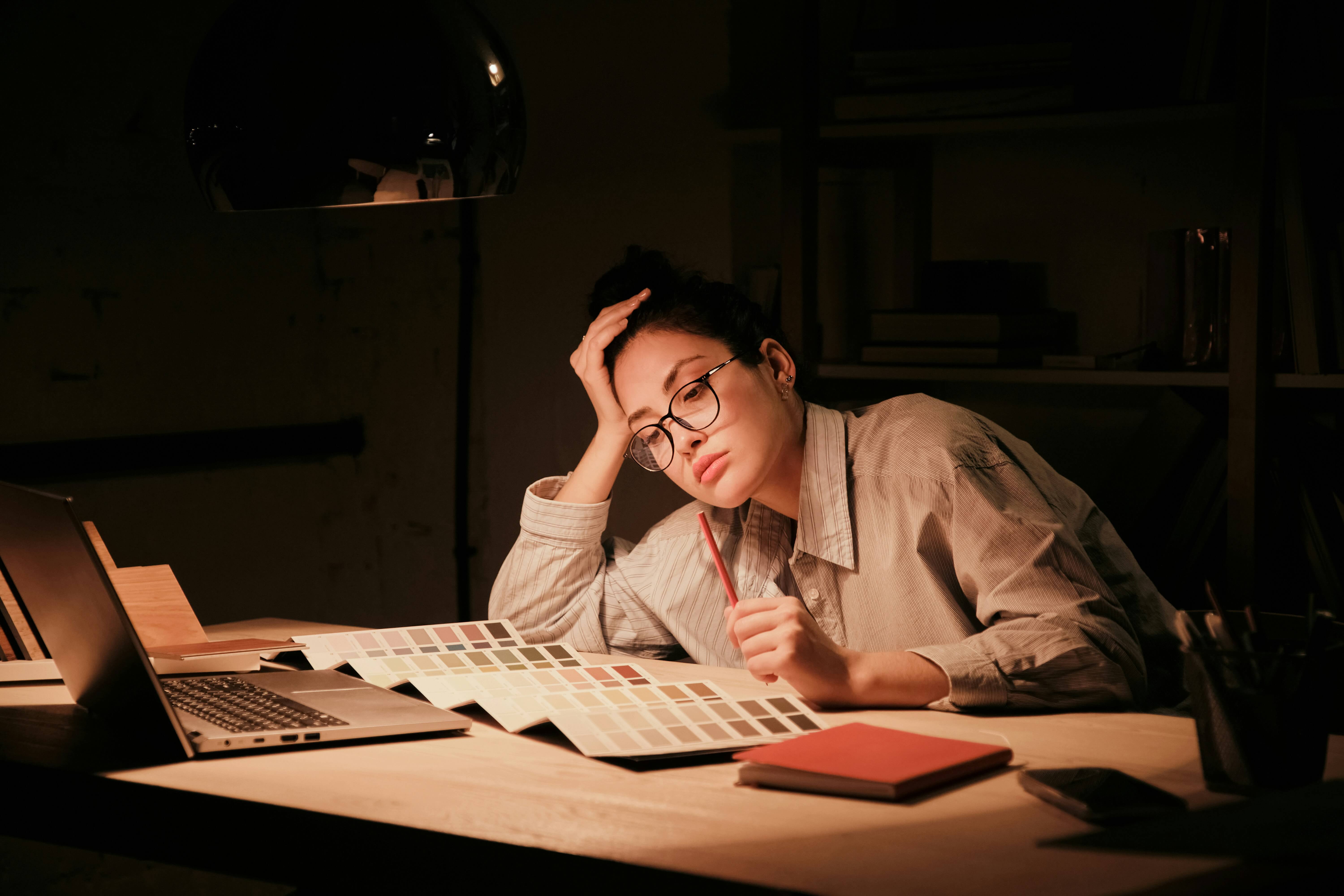 Woman feeling tired and unfocused while working late, representing low energy and fatigue