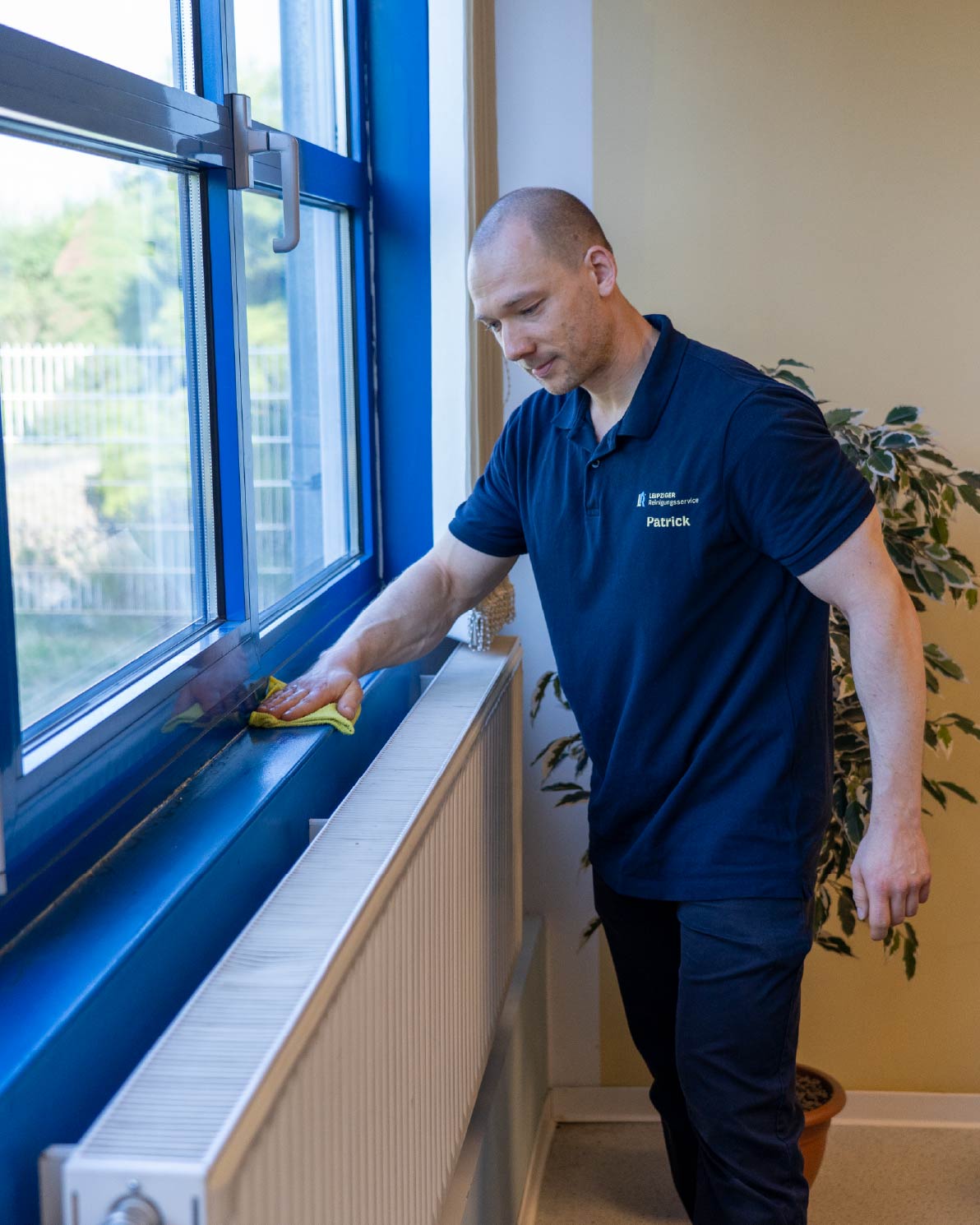 Patrick, Gründer des Leipziger Reinigungsservice, reinigt konzentriert eine Fensterbank im Detail