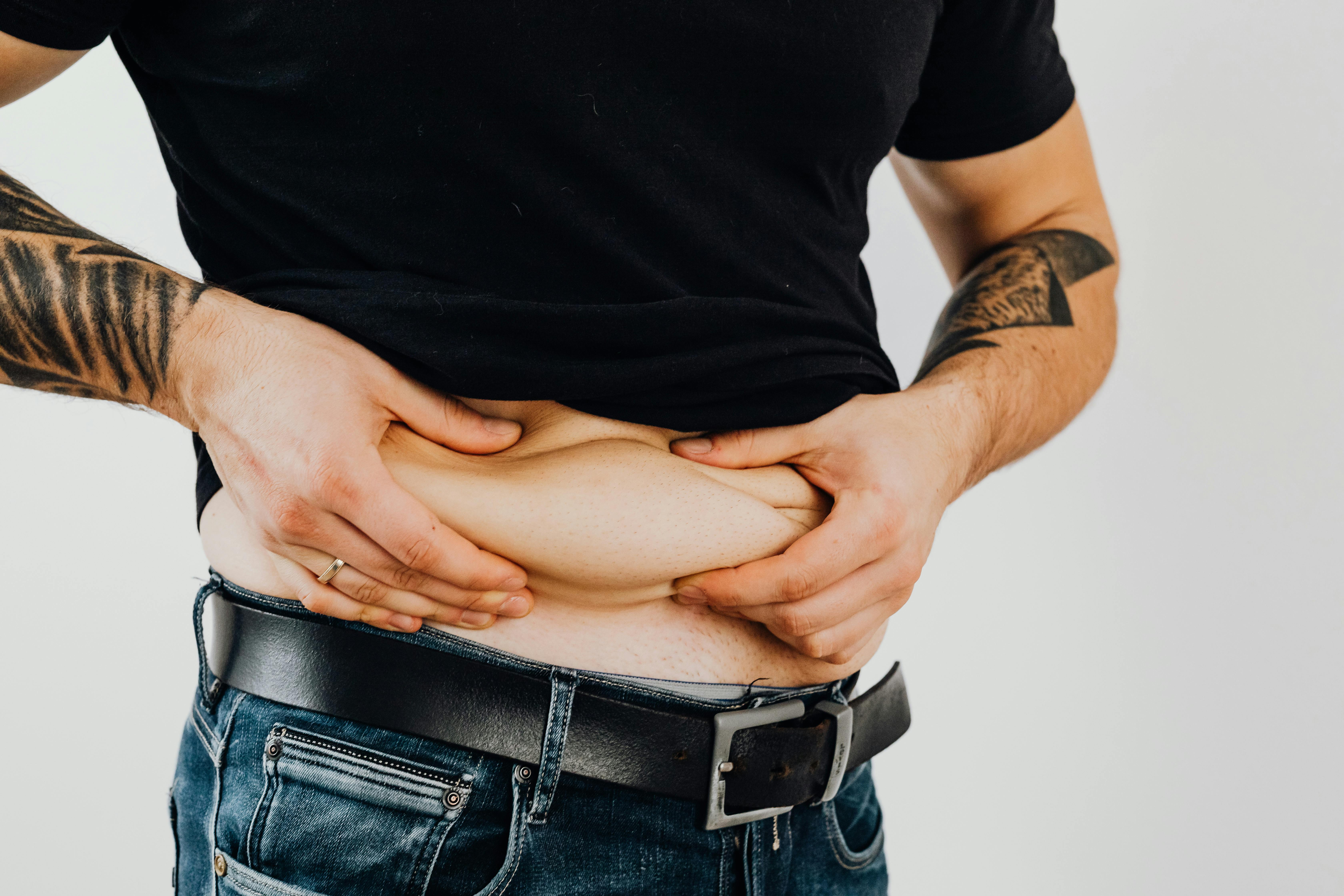 Man pinching his midsection showing stubborn belly fat