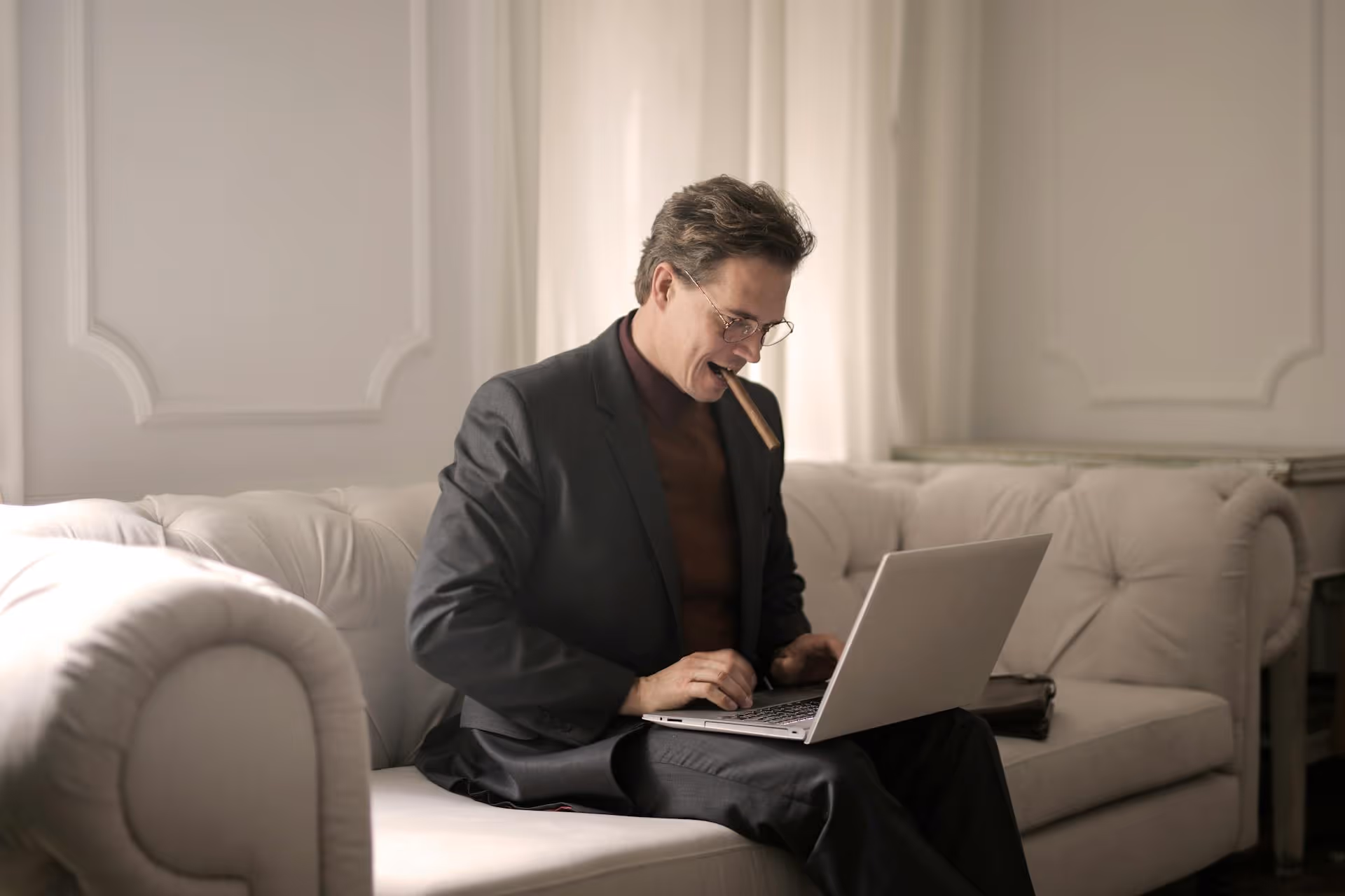 Business professional working on a laptop while seated on a sofa in a modern office lounge.